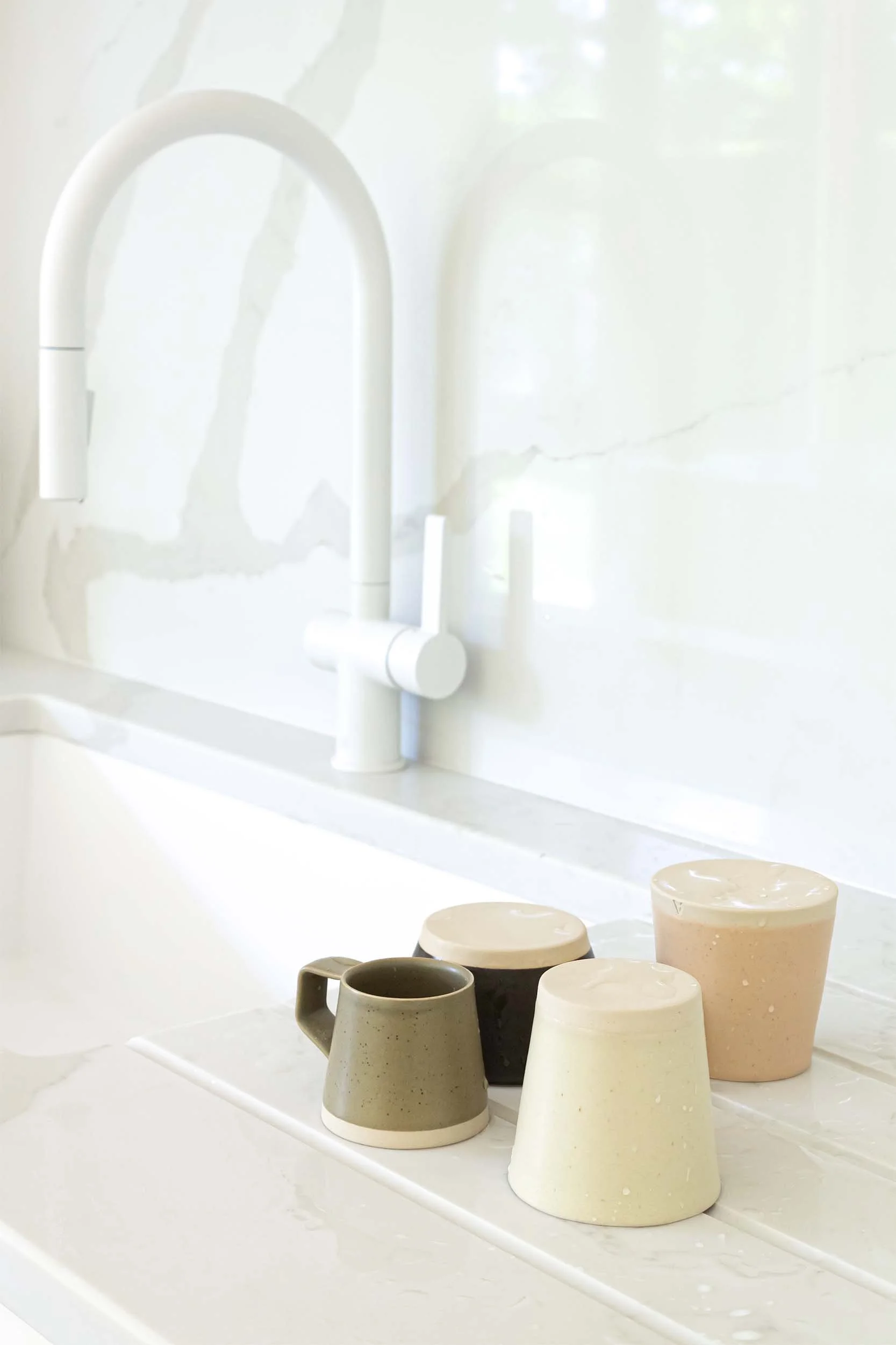 white tap with wet cups draining on the drainage grooves