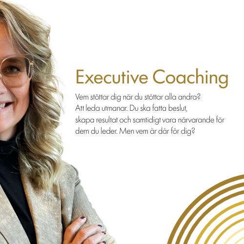 En kvinna med blont, lockigt hår, glasögon, gul skjorta, svarta byxor och smycken sitter i en ljus fåtölj och pratar eller förklarar.