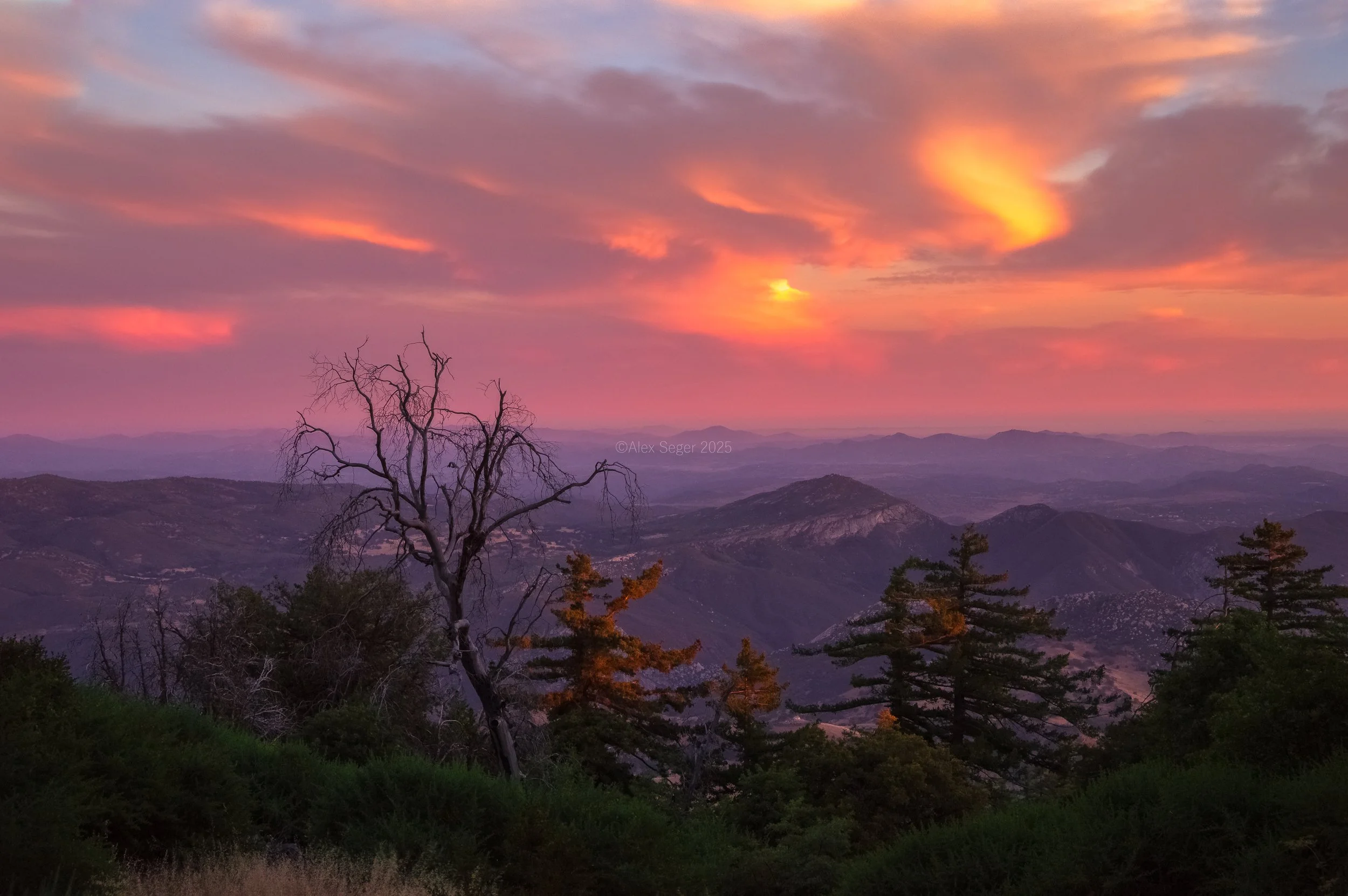 A vibrant sunset over Palomar Mountain in San Diego, CA. Rolling layers of mountains and trees compliment this classic sunset.