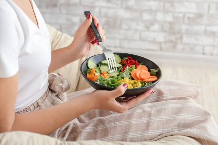 Persona sosteniendo un plato de ensalada con verduras frescas basada en una alimentacion antiinflamatoria.