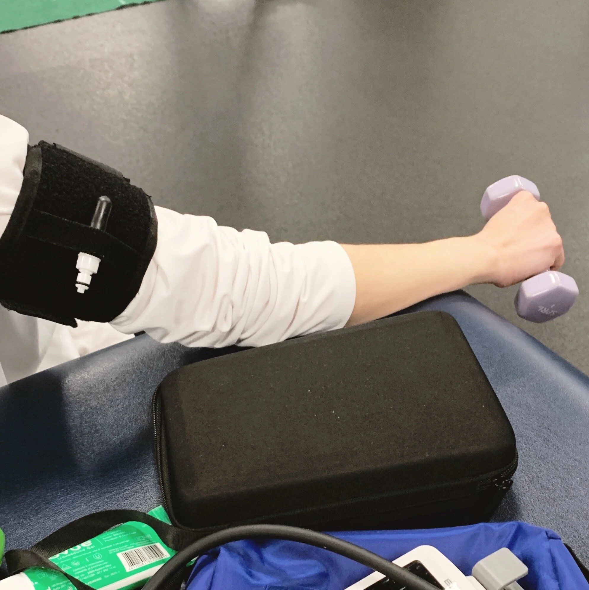 Patient with a blood pressure cuff monitored by a doctor of physical therapy overseeing blood flow restriction training post-injury