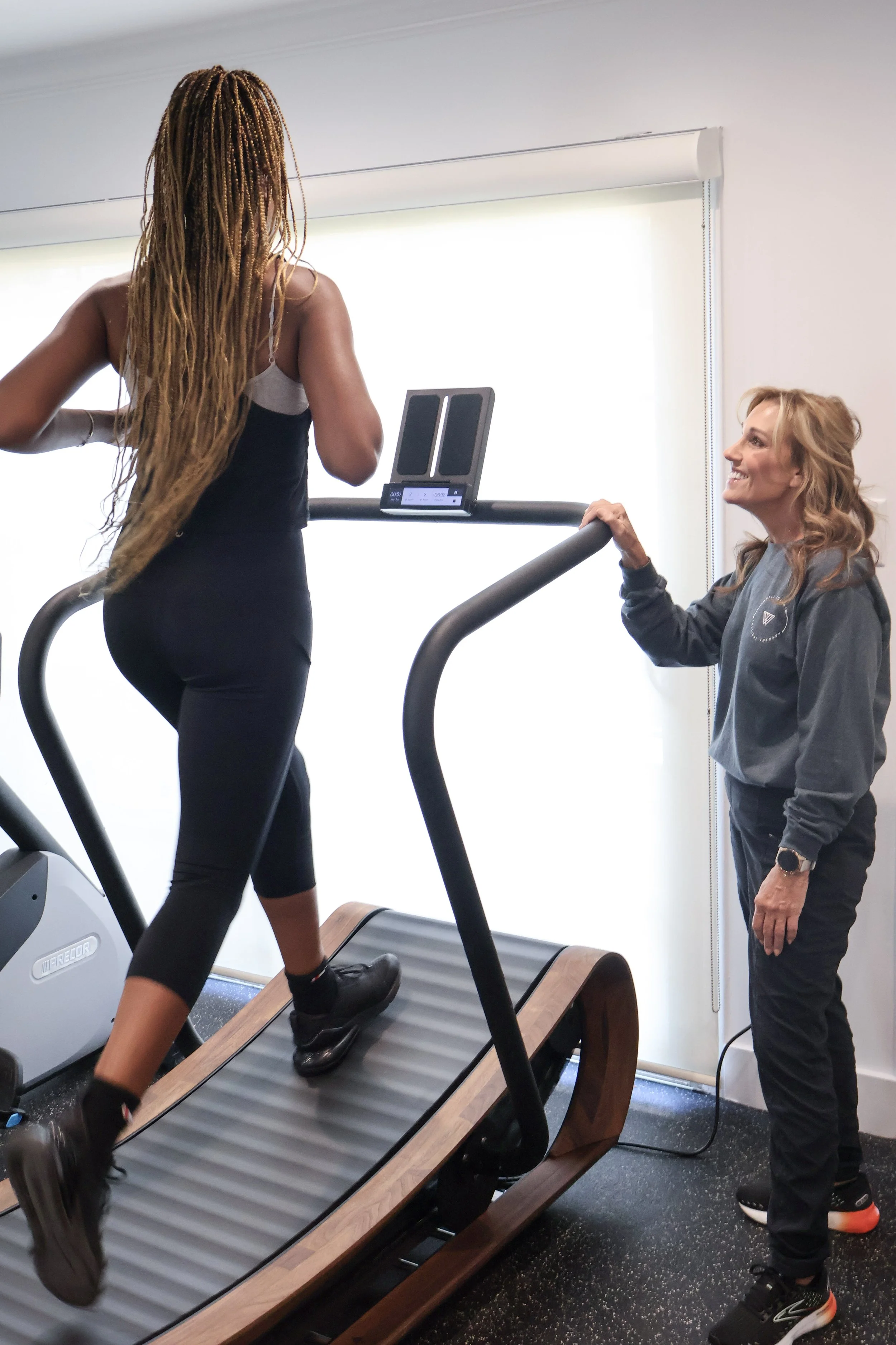 Doctor of physical therapy assessing movement of a patient running on a treadmill