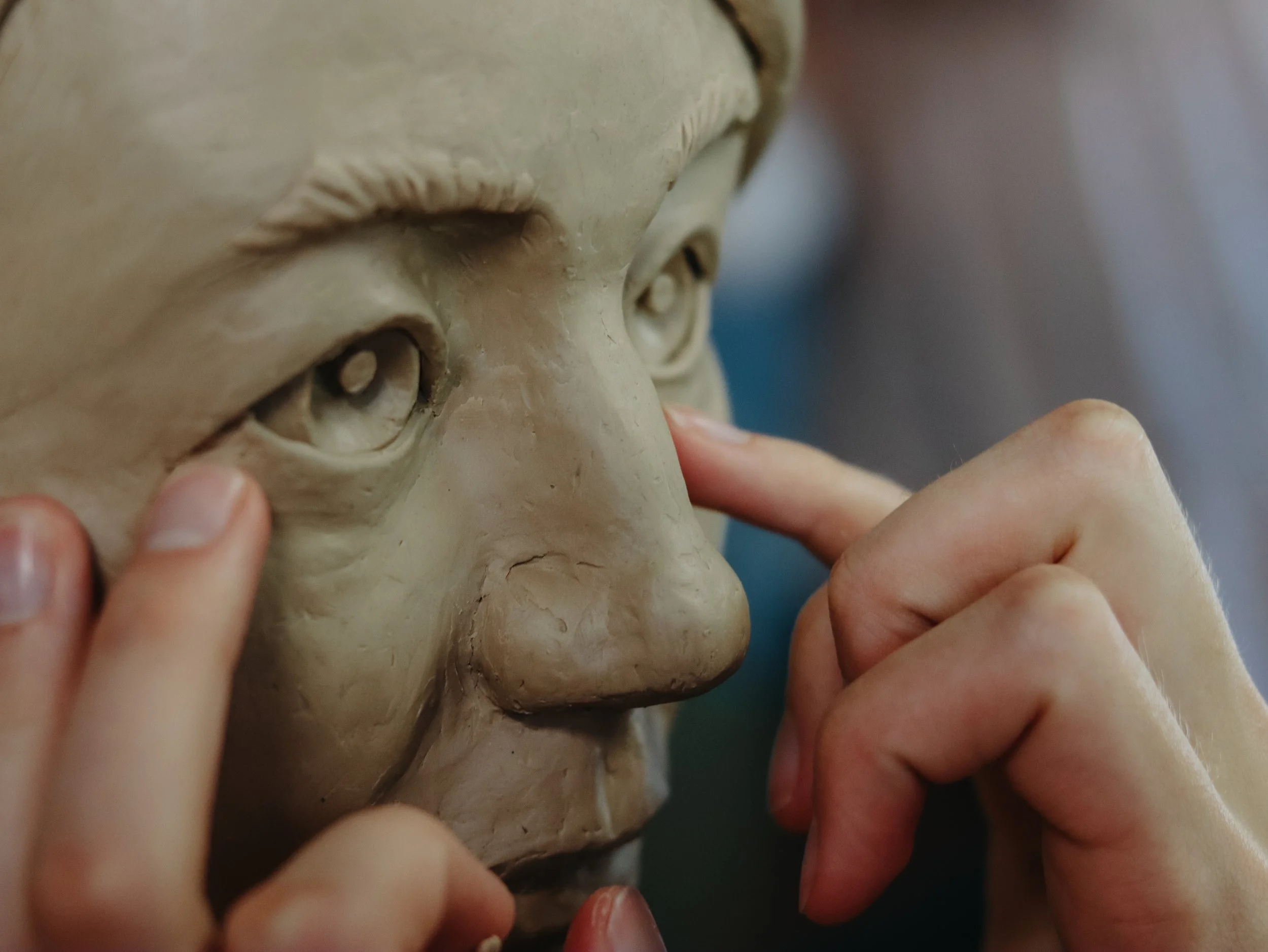 Close-up of hands working on a detailed sculpture or model at a small classical school.