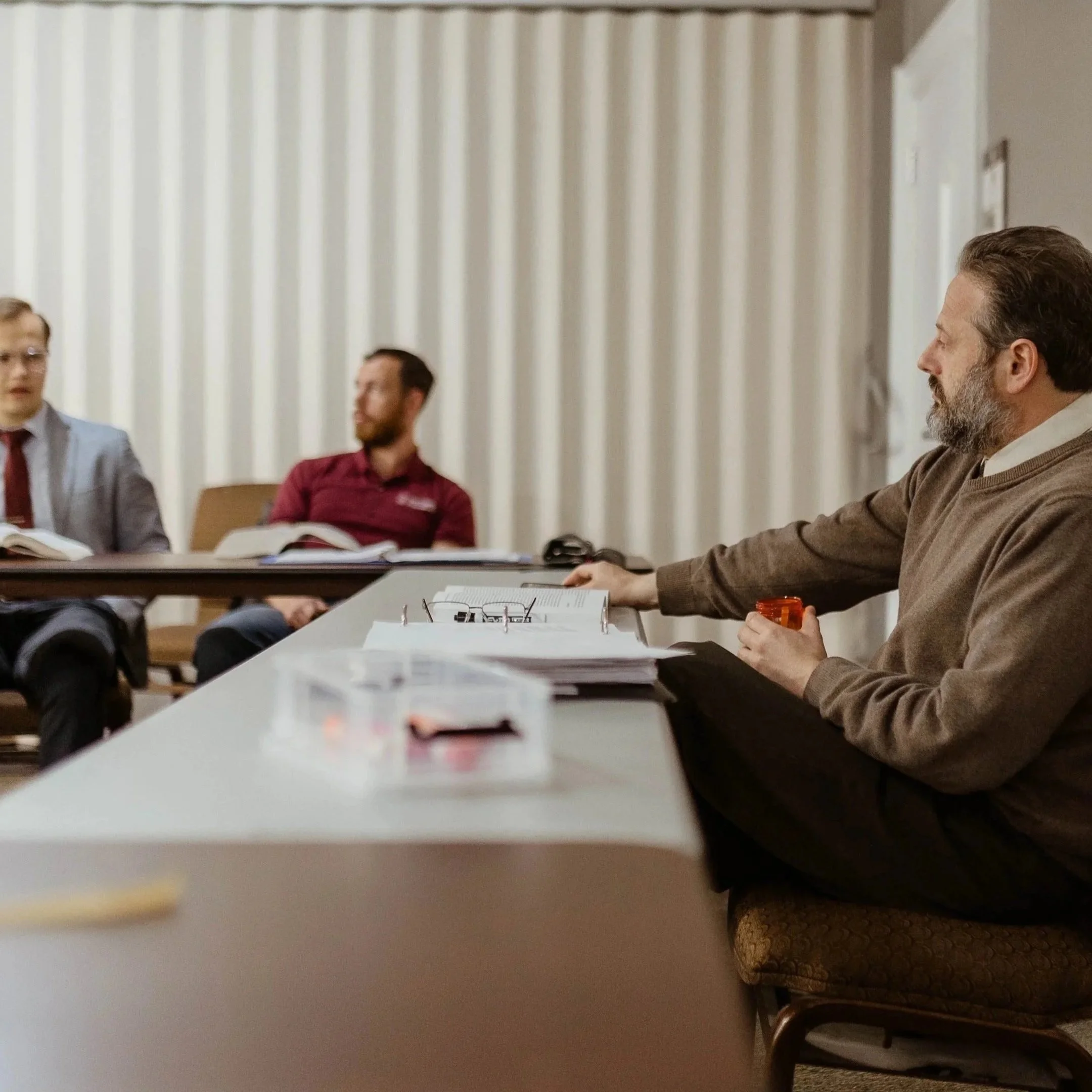 People sitting at a table in a room from a small liberal arts school, engaged in discussion.