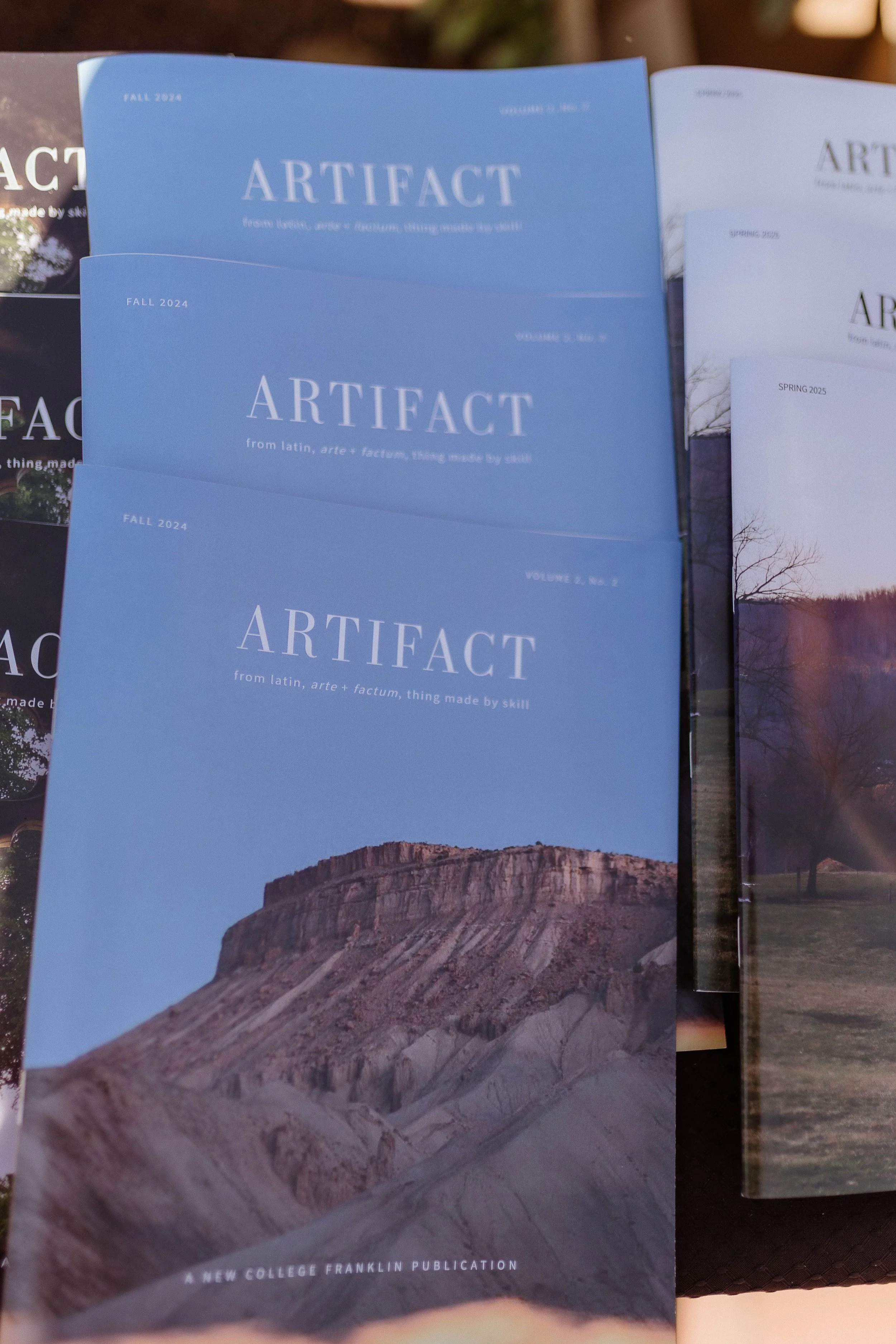 A magazine titled 'Artifact' with a cover photo of a mountain or hillside landscape, printed by a liberal arts school.