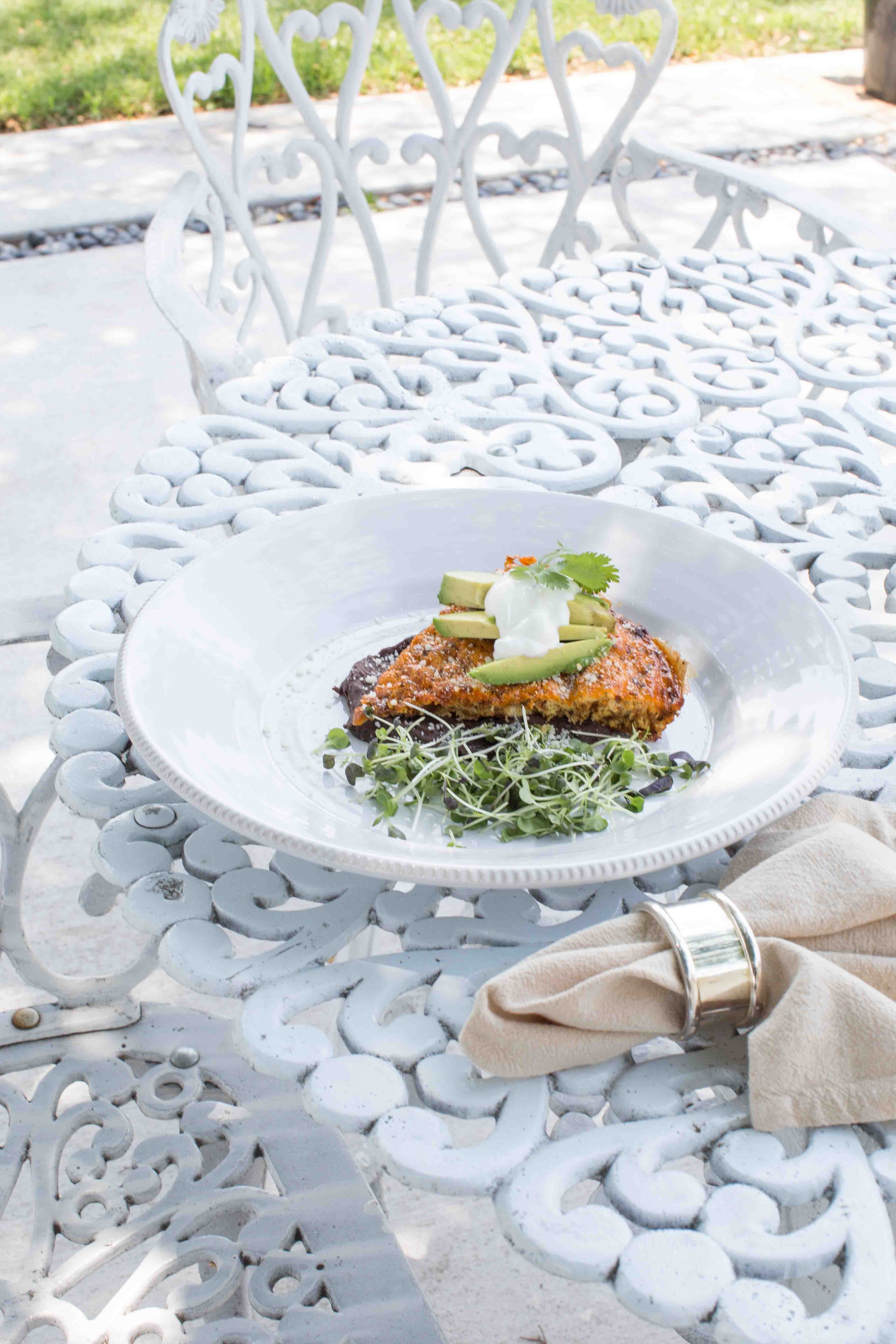 Breakfast on Patio - Chorizo Frittata Topped with Avocado, Cream, and Cotija Cheese Over a Black Bean Puree