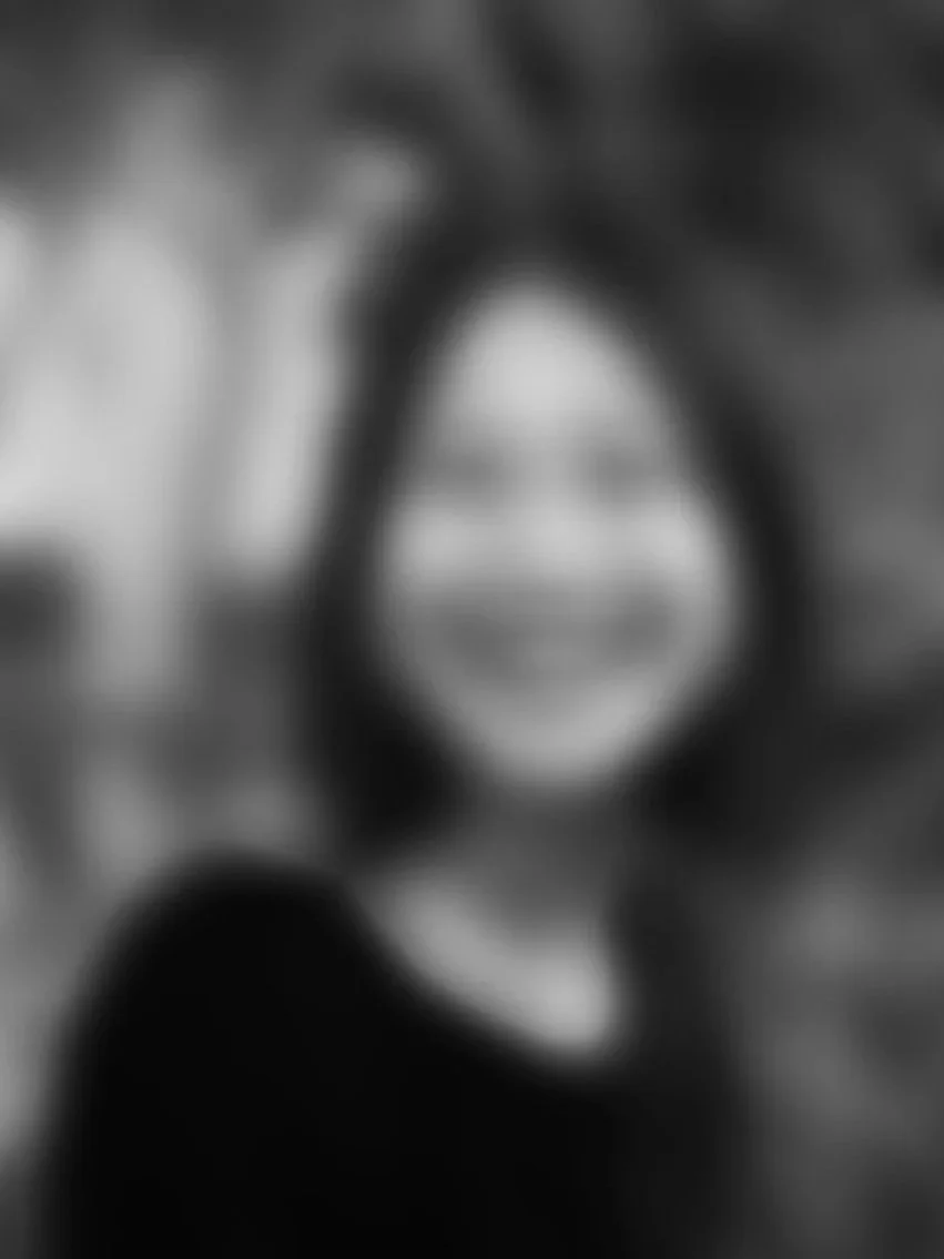 Blurry black-and-white portrait of a woman with curly hair smiling.