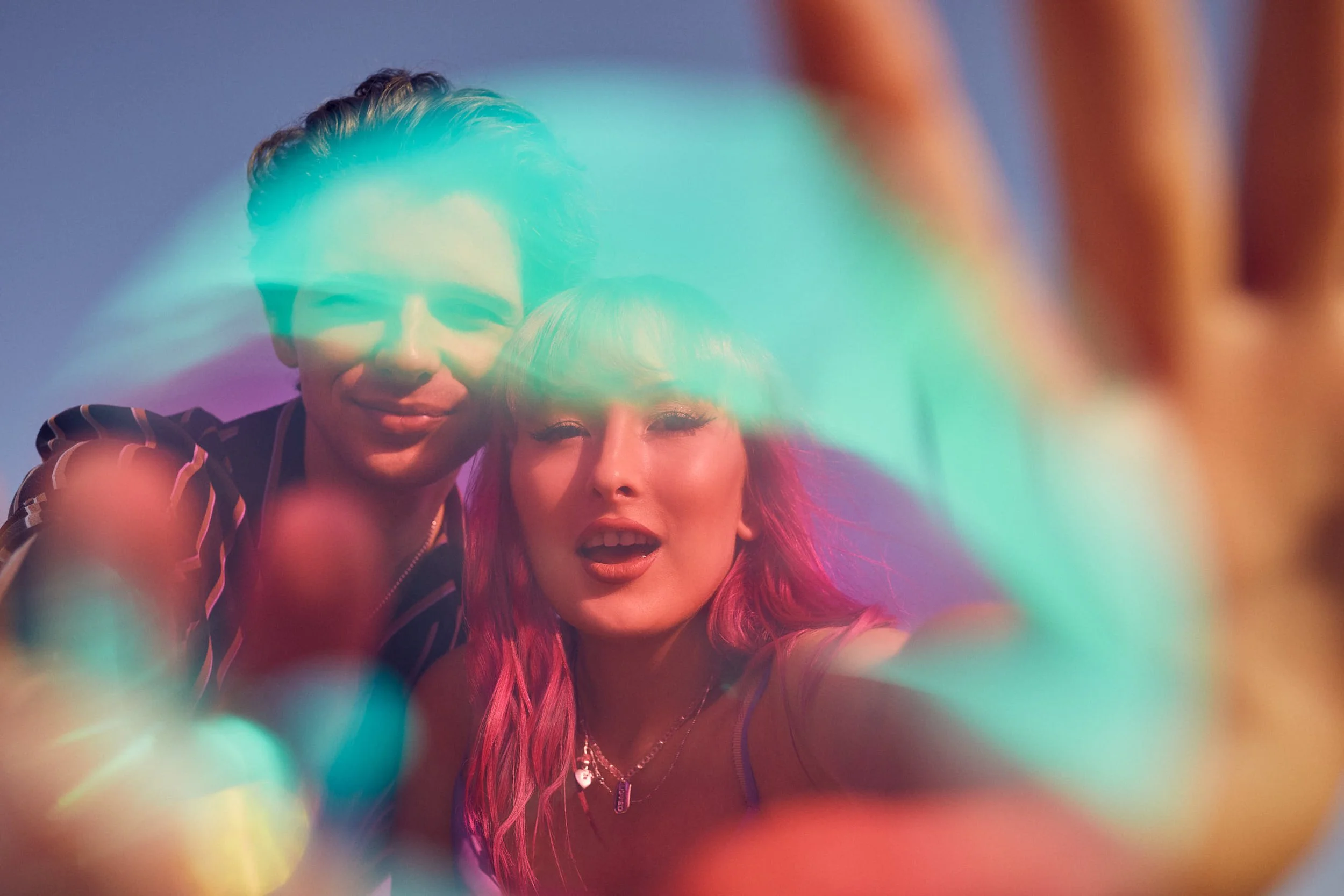 Two young people taking a selfie through a colorful neon-lit ring.