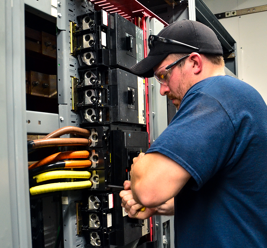 Technician performing assembly and testing on UL891 switchboard circuit breakers