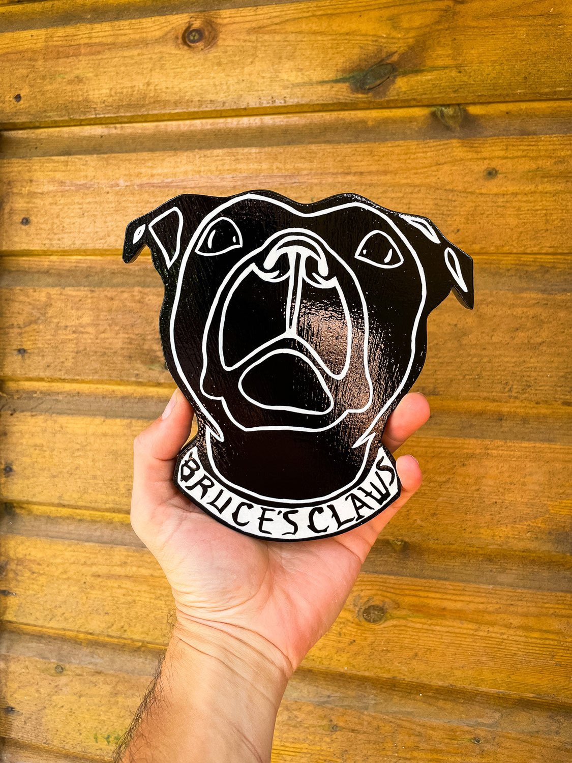 A handcrafted woodcut sign featuring bold, vibrant hand-painted colours, making the design pop, showcasing the precision and artistry that goes into each piece. This piece is for Bruce's Claws, a pet pampering company based in Midsomer Norton, it's a