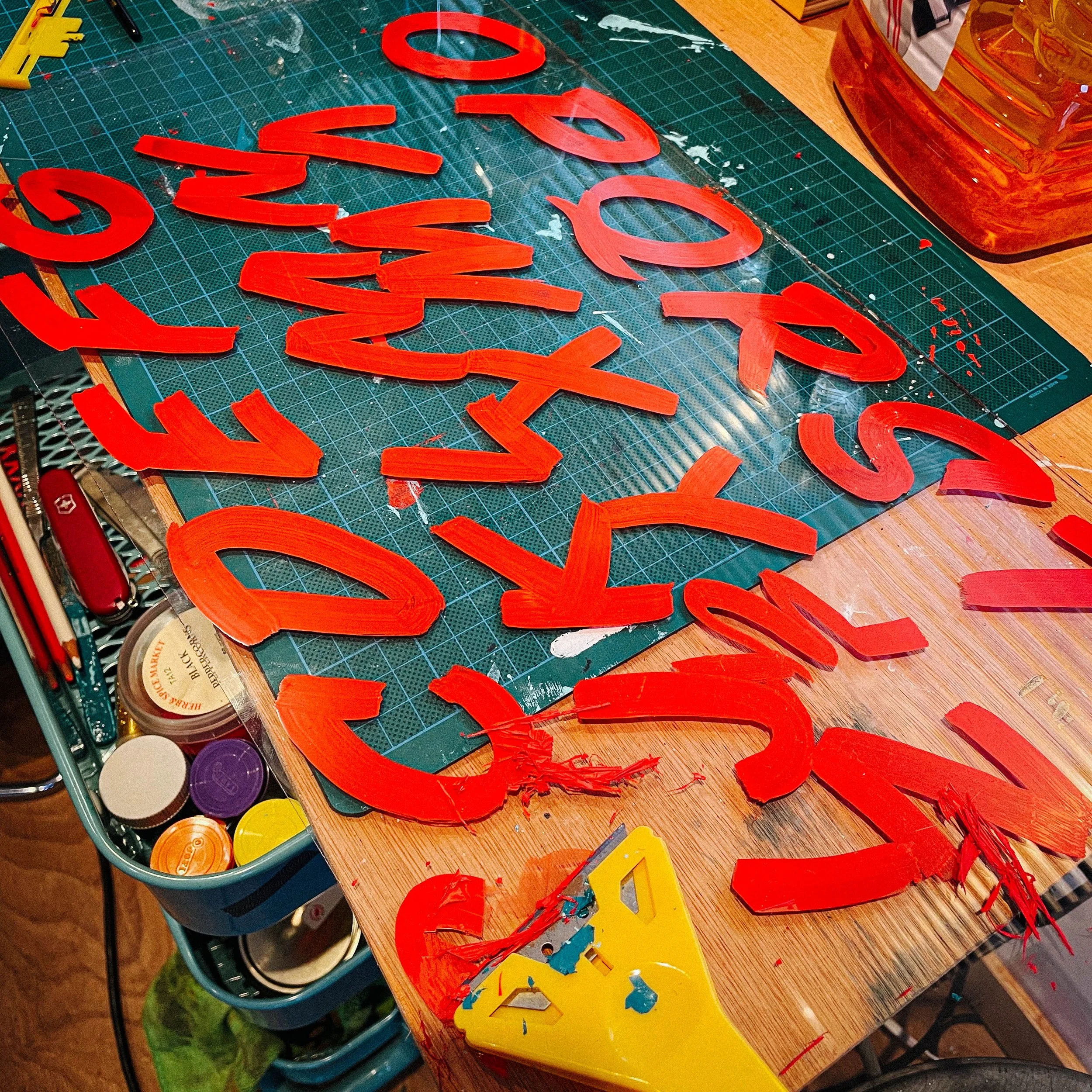 A behind-the-scenes shot of Rich painting letters, capturing the early stages of his creative process.