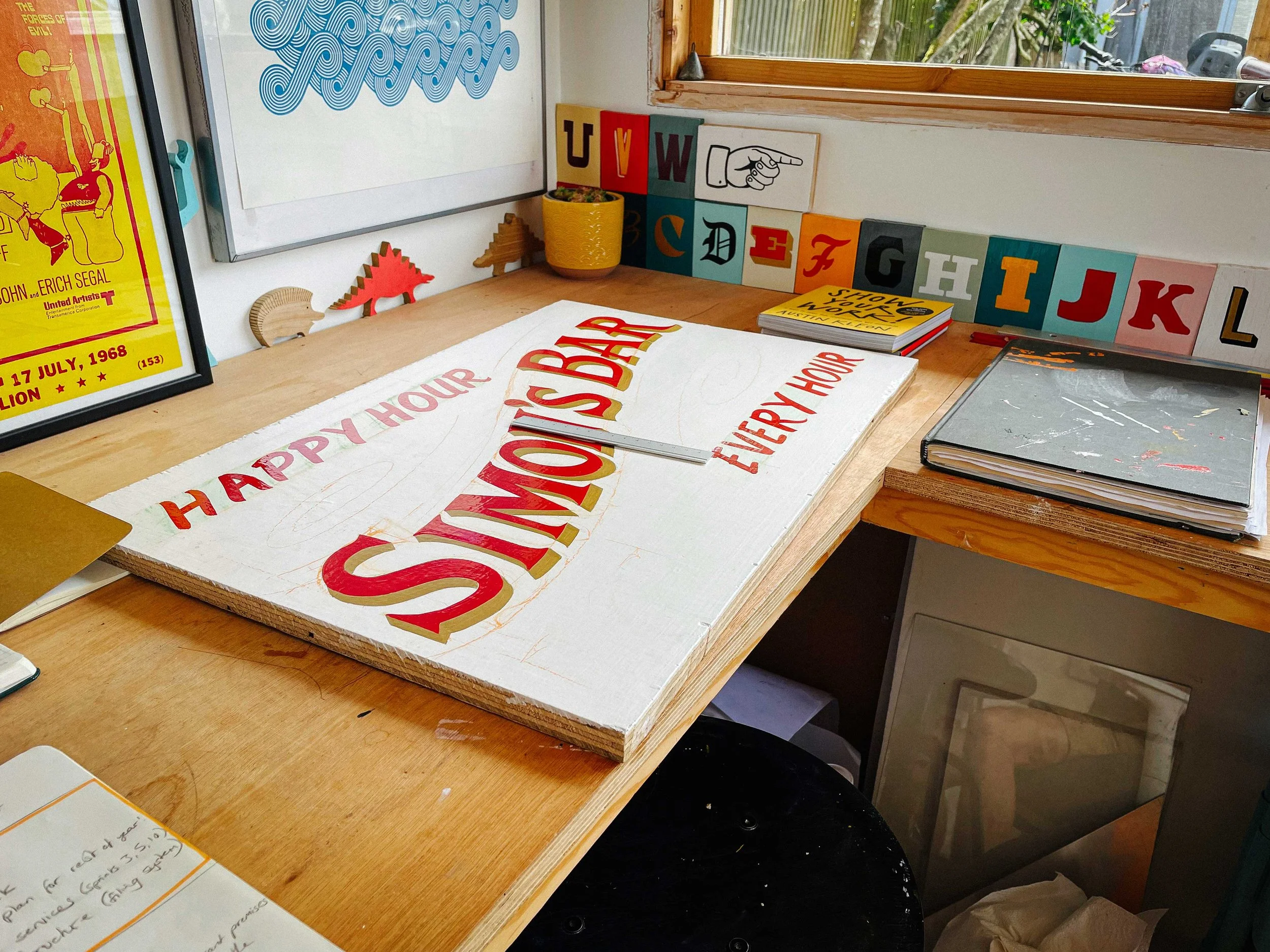 A behind-the-scenes shot of Rich sketching and painting a sign for a client, capturing the early stages of his creative process.