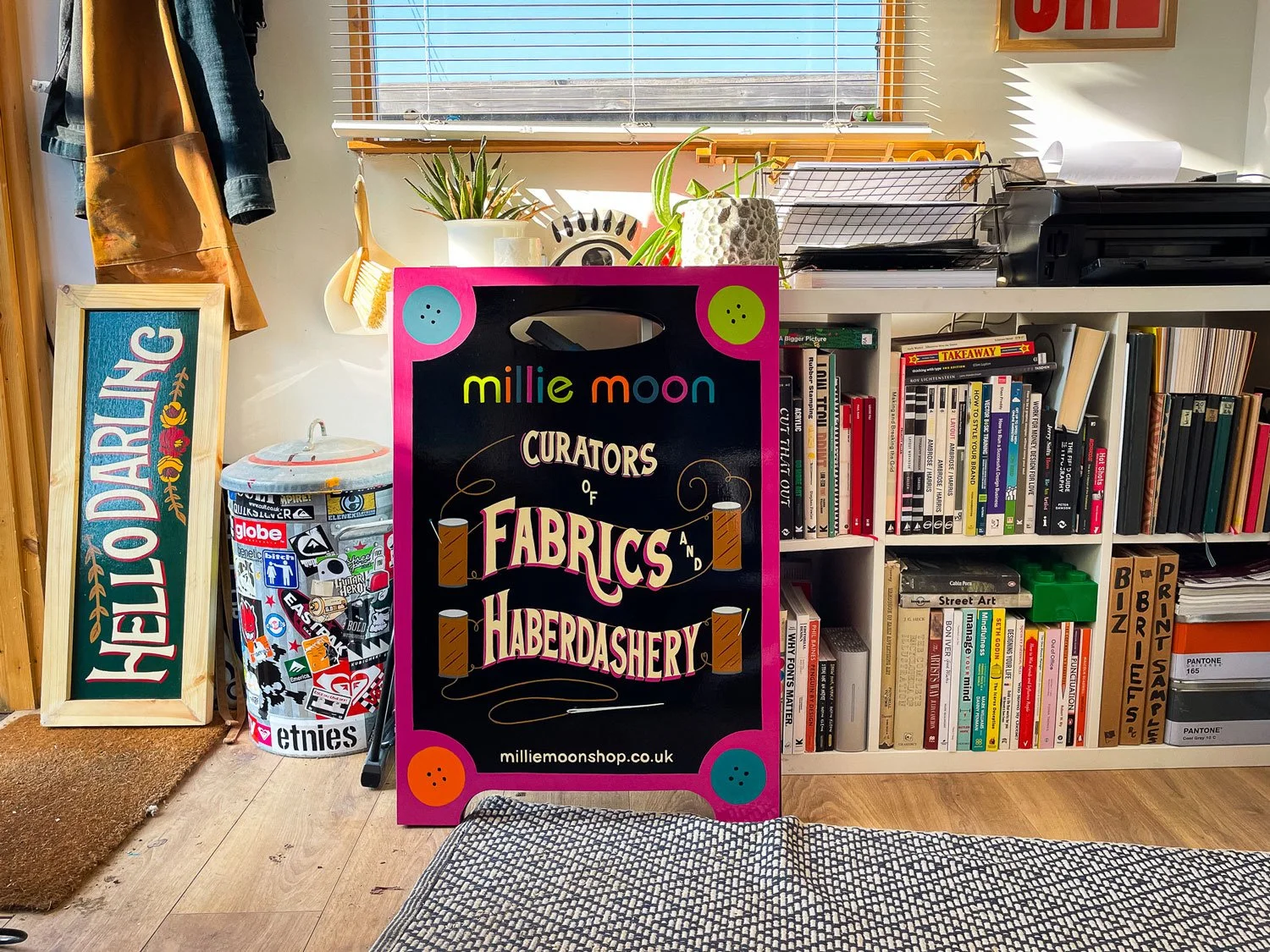 A hand-painted, double-sided A-Board for Millie Moon in Frome featuring bold, custom lettering in vibrant colours, showcasing the craftsmanship of Rich C Studio.