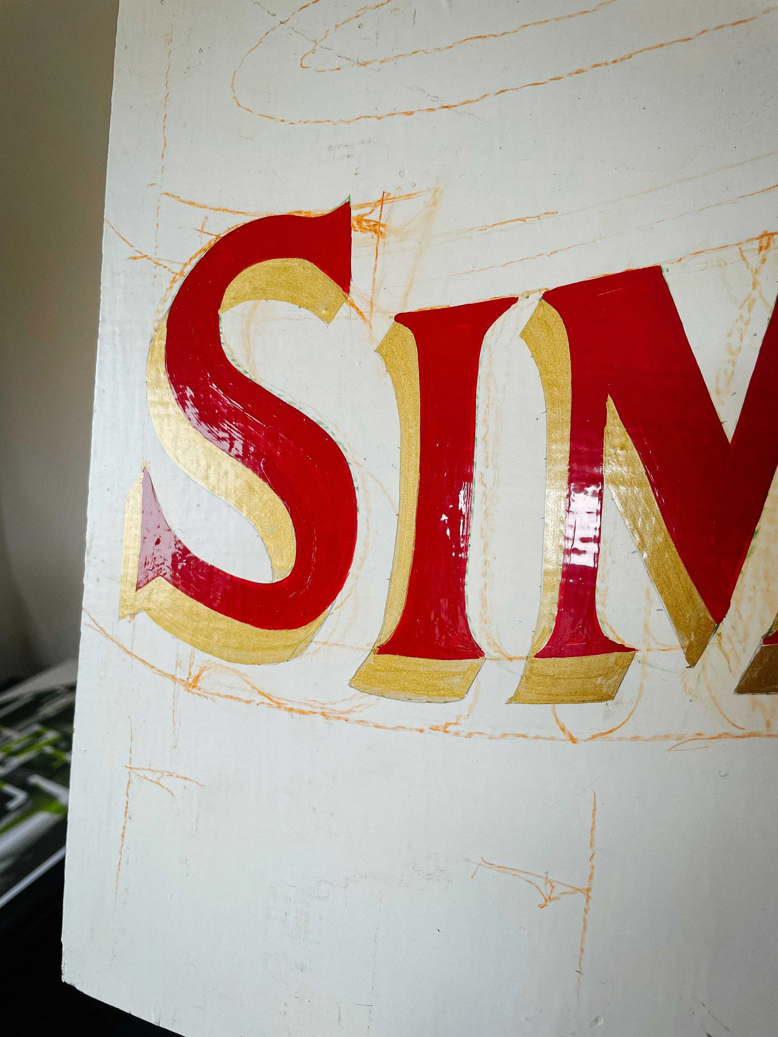 A behind-the-scenes close-up shot of Rich painting a sign for a client, capturing the early stages of his creative process.