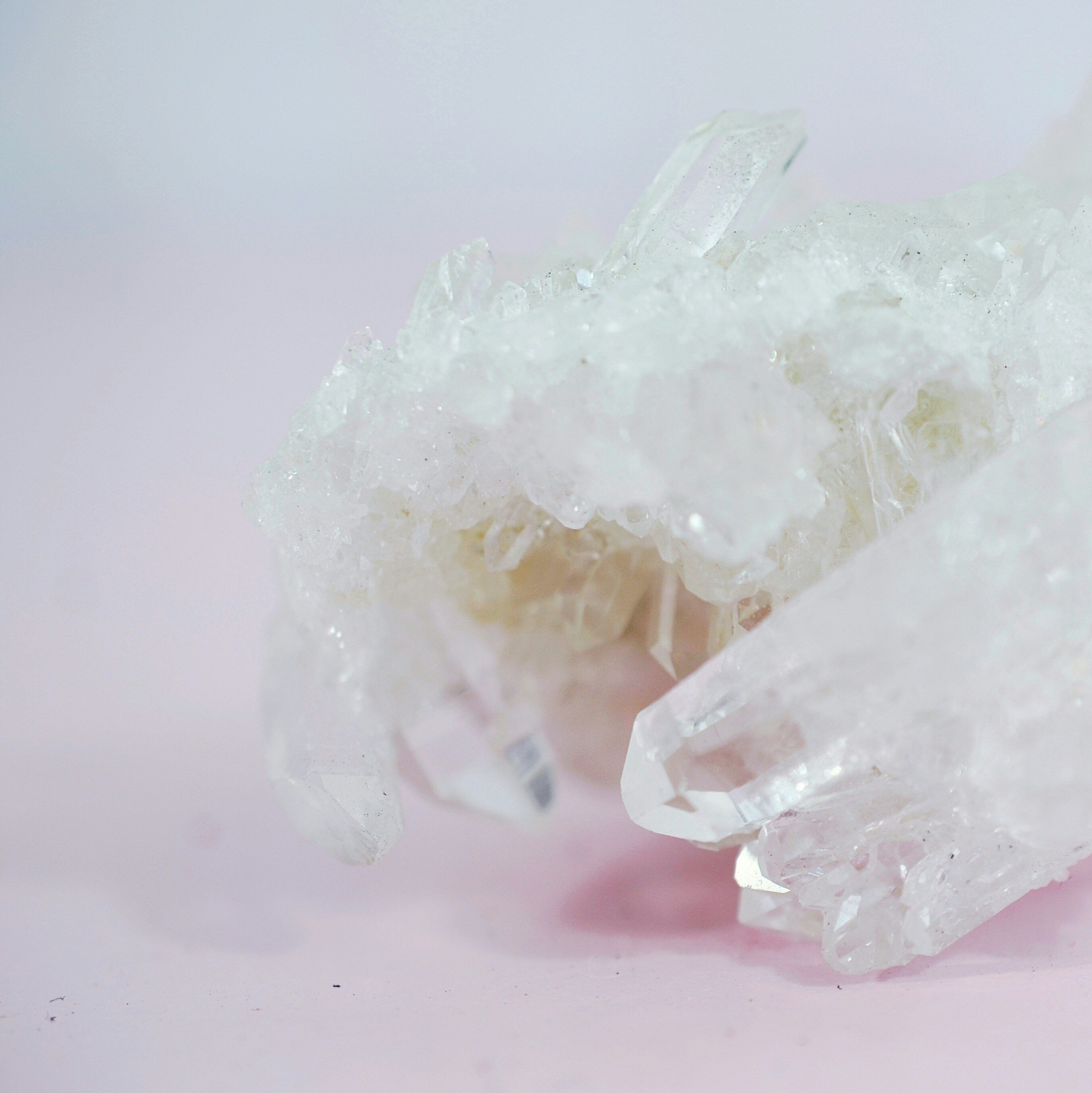 Close-up of clear quartz crystals on a light pink background.