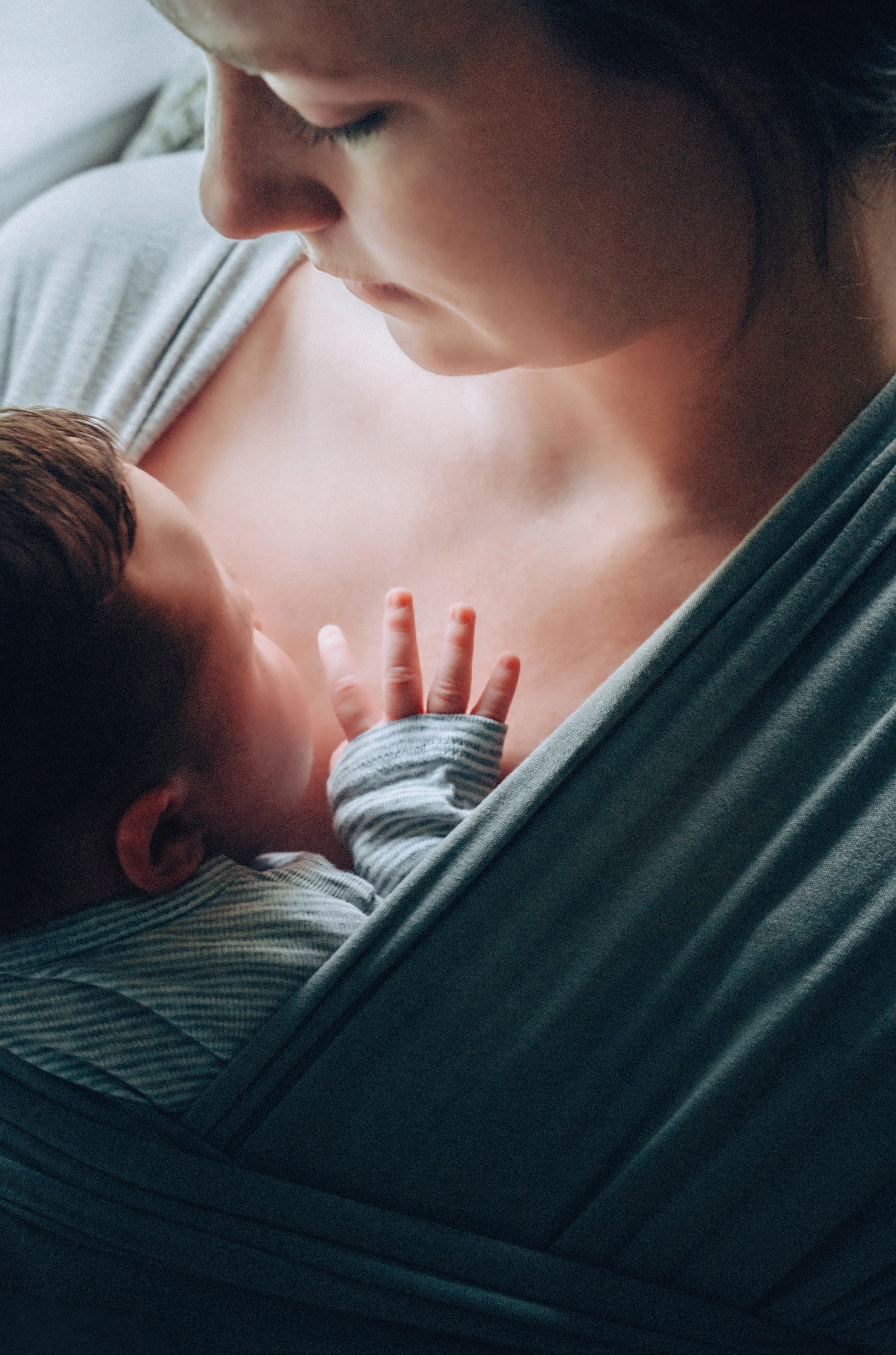 shannon lu shan documentary & lifestyle family photographer Arnprior , A young woman and a baby are lying together, with the woman positioned above and looking down at the baby, who is resting on her chest. T