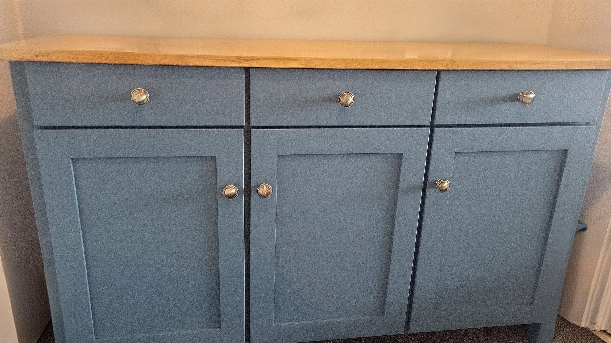 A blue wooden cabinet with six drawers and two doors, topped with a light wood surface.
