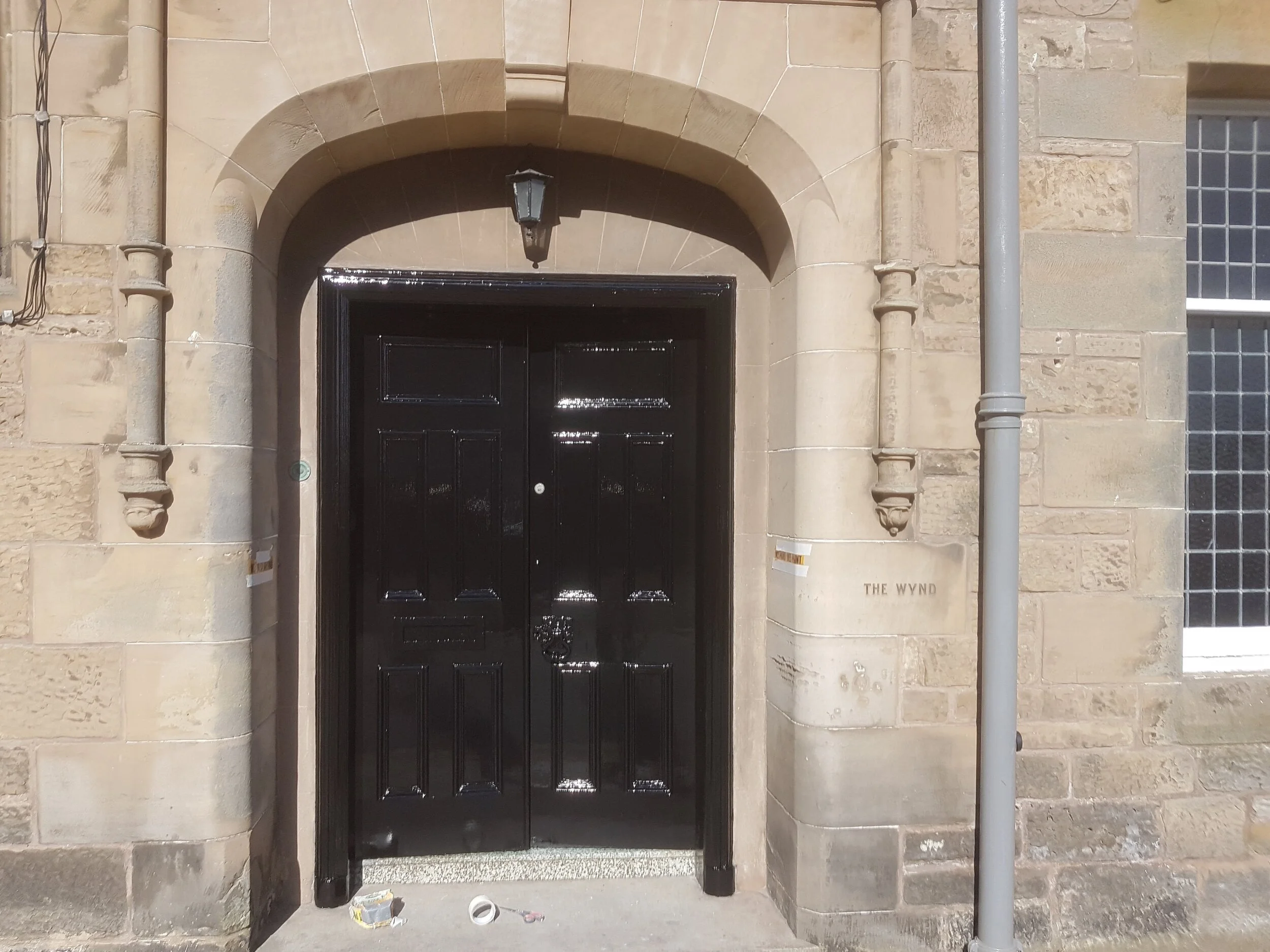 Large black double doors in an arched stone entrance, 