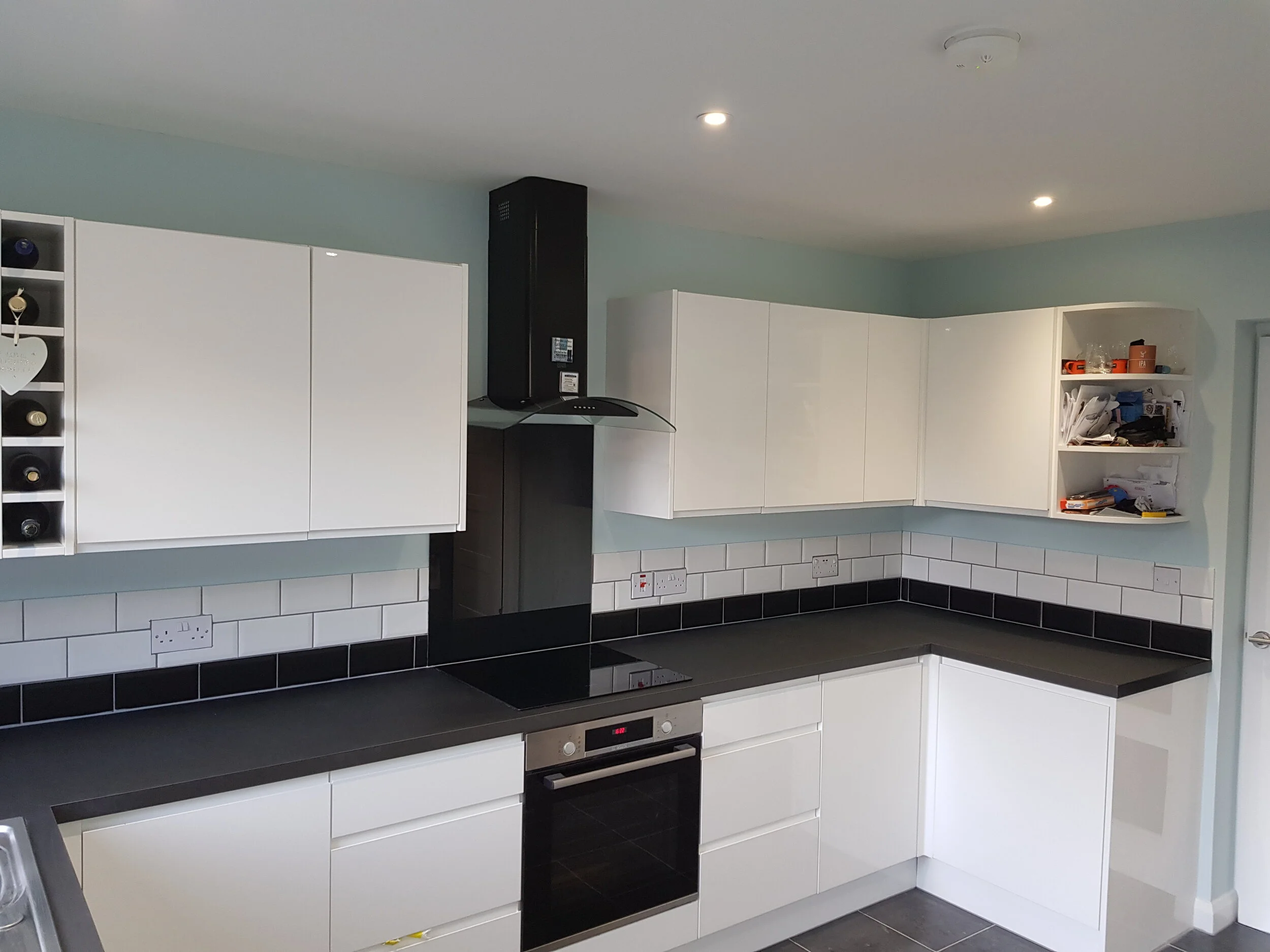 Modern kitchen with white cabinetry, black countertops, integrated appliances, and a tiled backsplash.