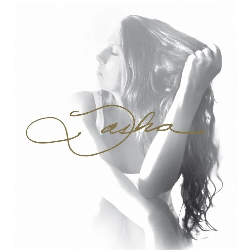 Black and white photo of a woman with long, wavy hair, sitting with her eyes closed, holding her hair with one hand, with the word 'Aloha' written in gold cursive across the image.