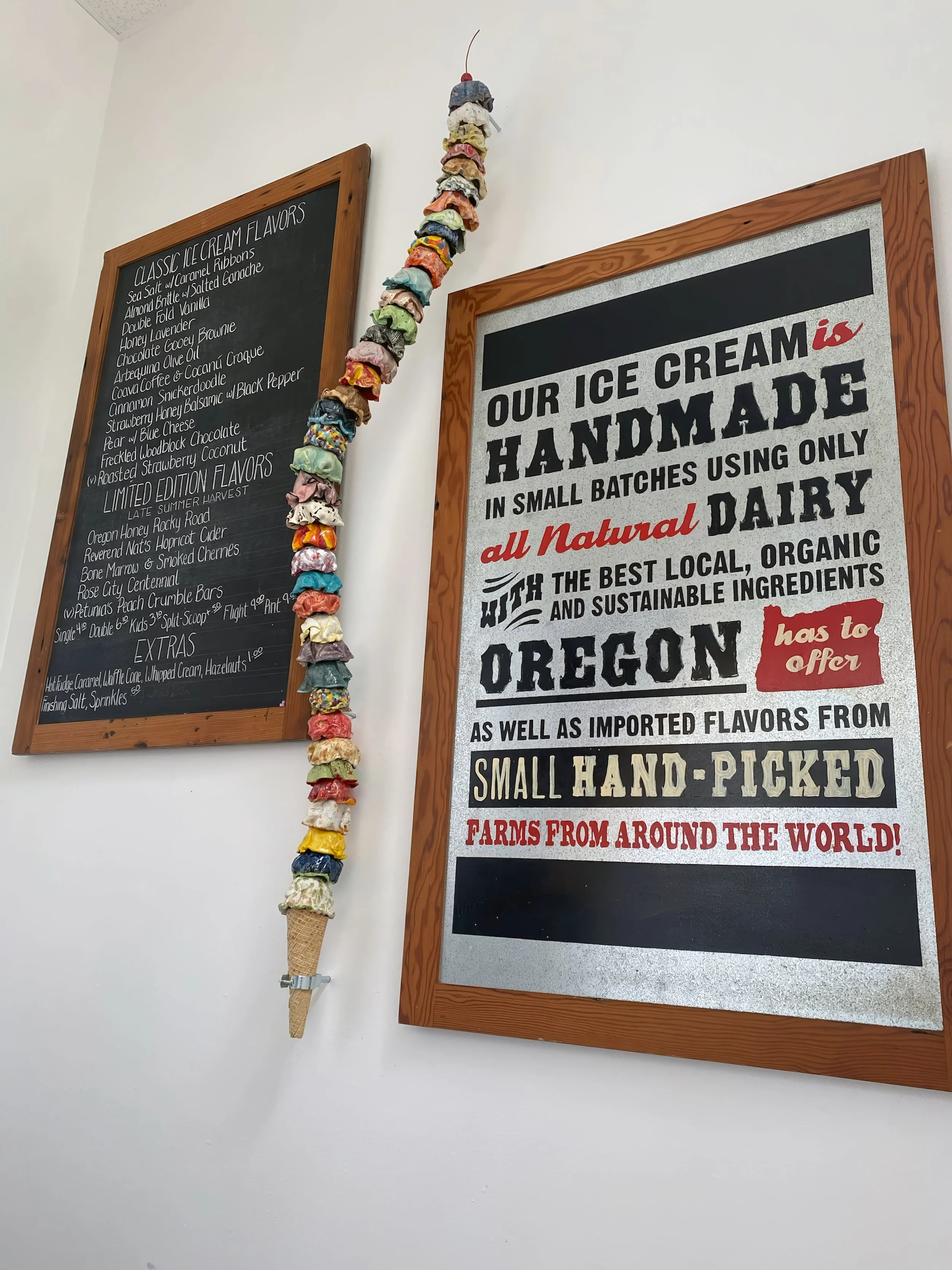 Decorative display of a bunch of colorful rock candy sticks hanging on the wall next to a menu board and an ice cream shop sign.