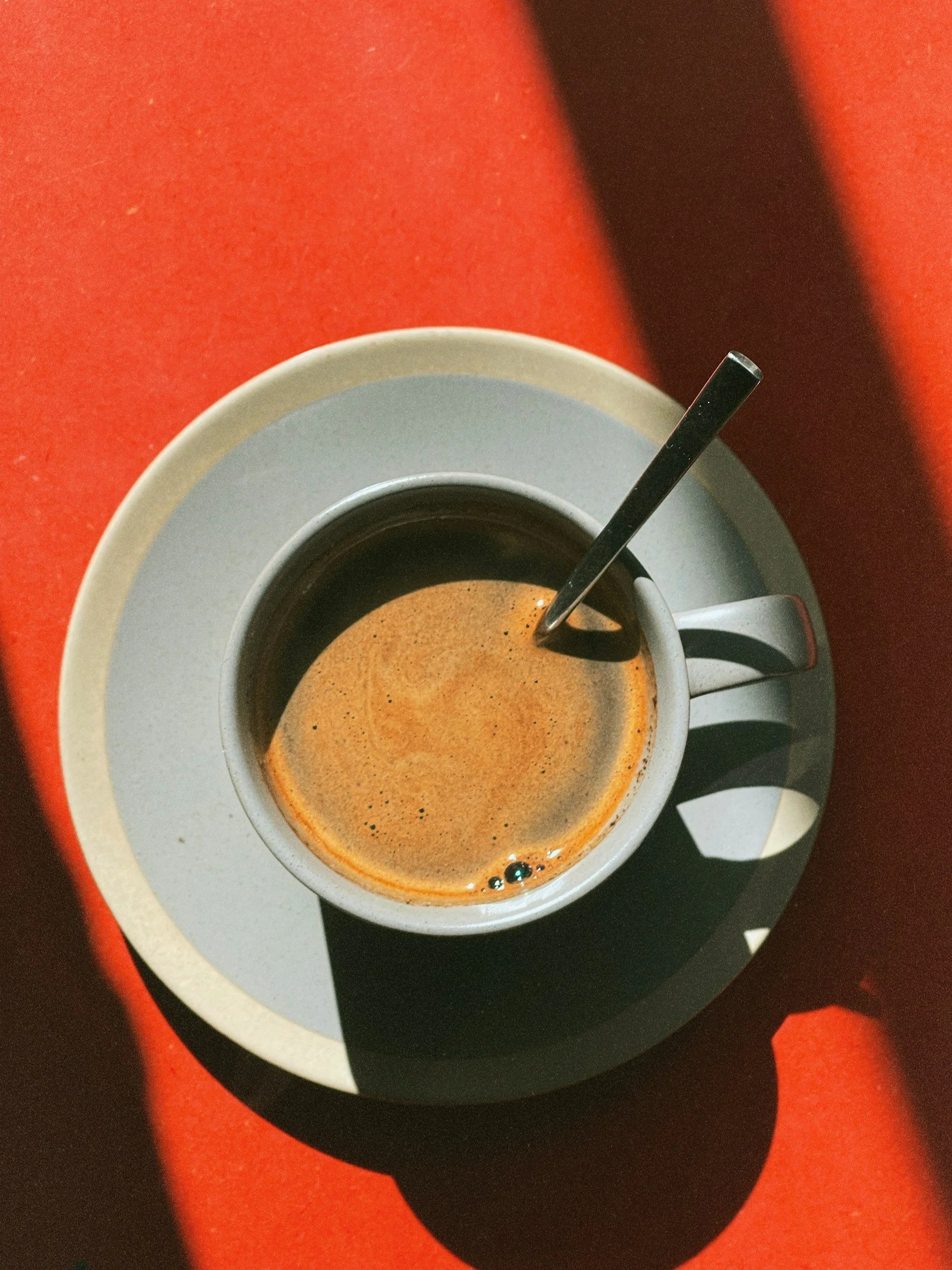 Overhead view of coffee cup and saucer with coffee and milk stirred with a spoon
