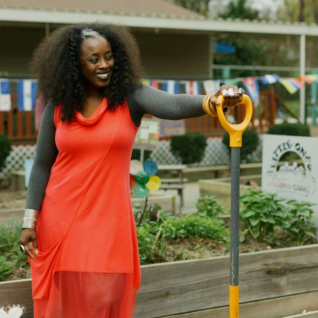 wande okunoren in an orange dress in a community garden holding a shovel
