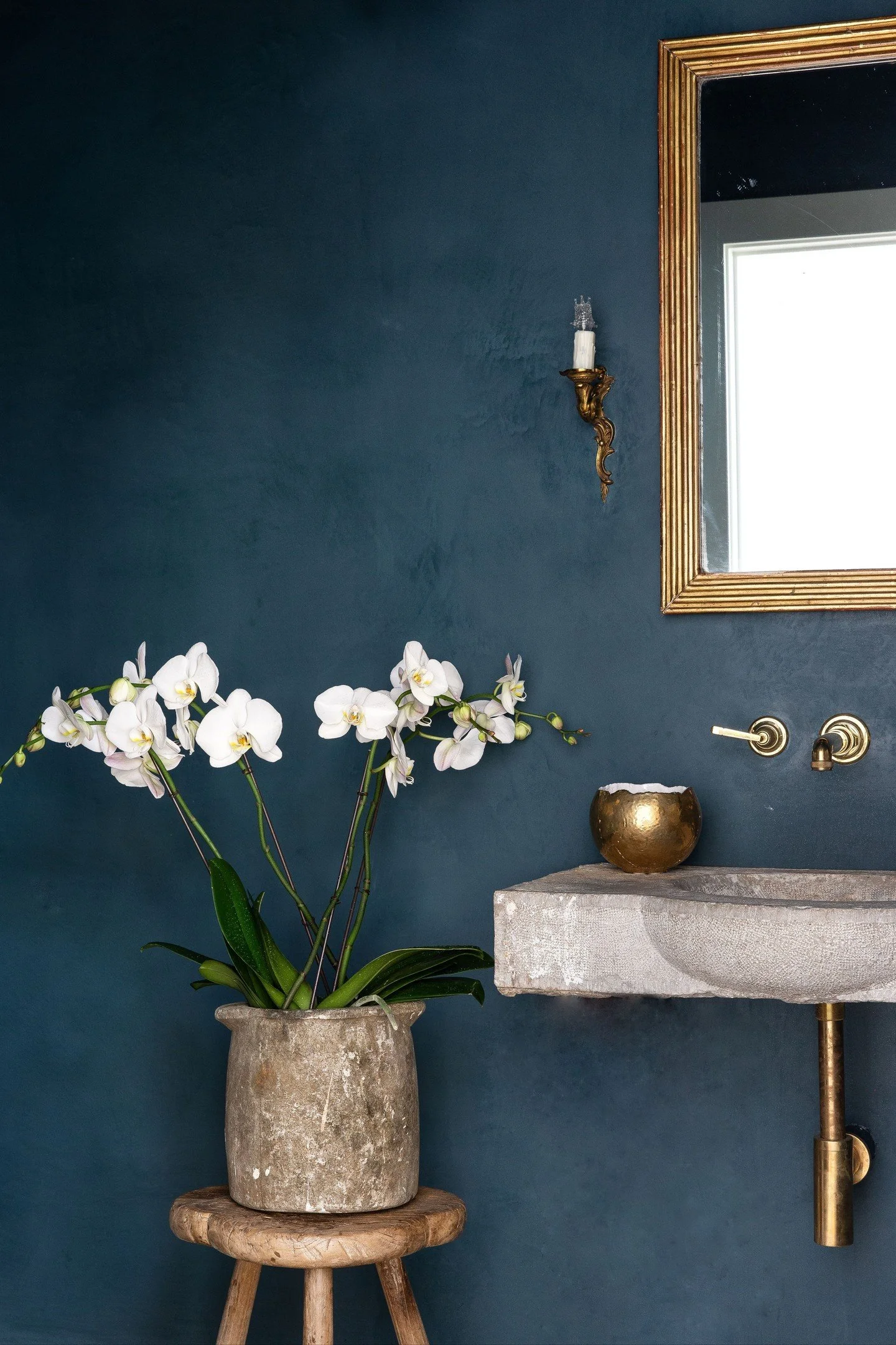 Designed around a reclaimed stone sink, every detail in this bathroom follows its lead. Plaster walls and a moody palette set the foundation, while gold accents add just the right amount of warmth.

A space where texture, material, and detail each ge