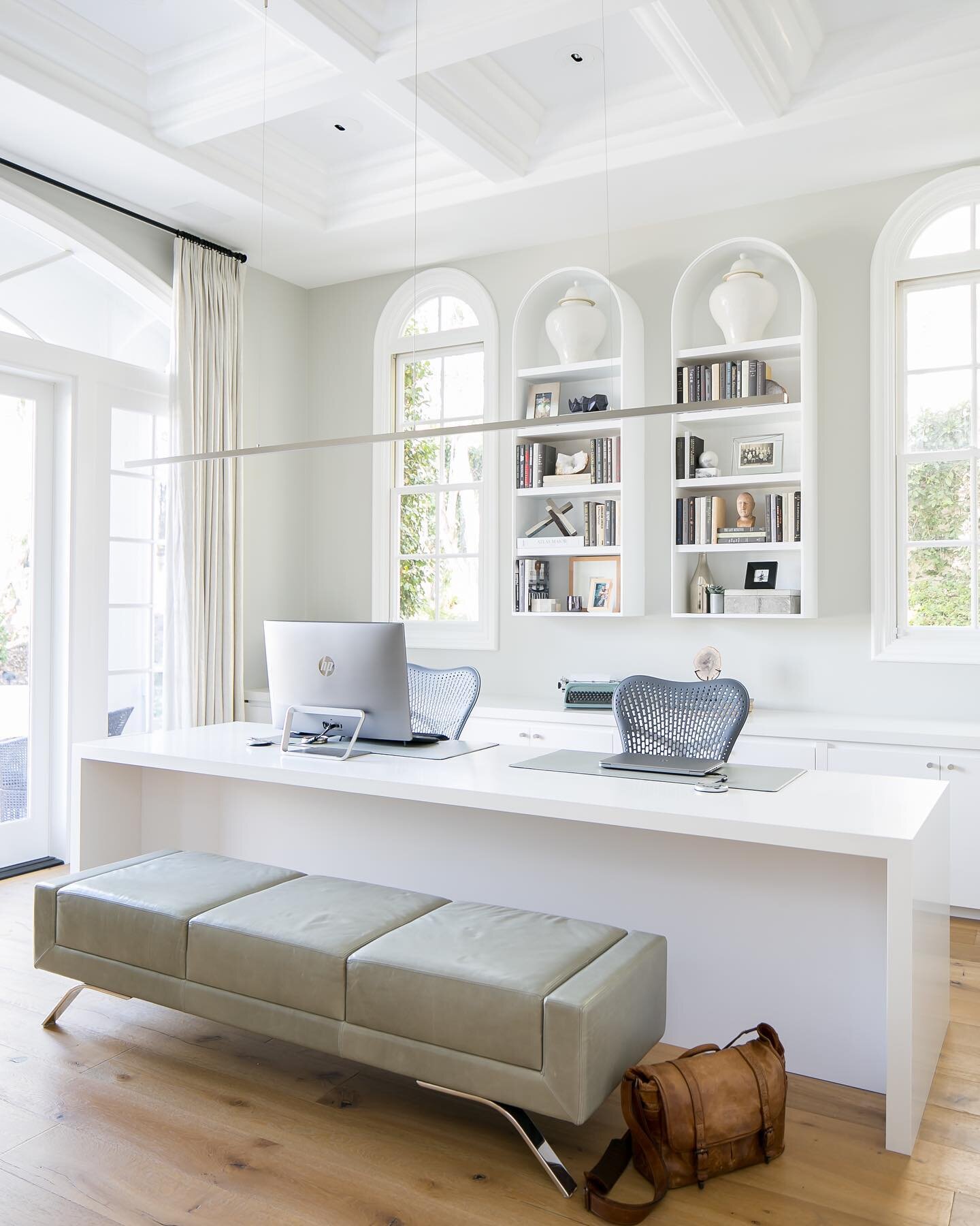 Mixing up some traditional and some contemporary in this home office. #archedbookcase #homeoffice #homeofficeideas #cotodecaza #archedwindows #leatherbench #whiteroom #interiordesigner