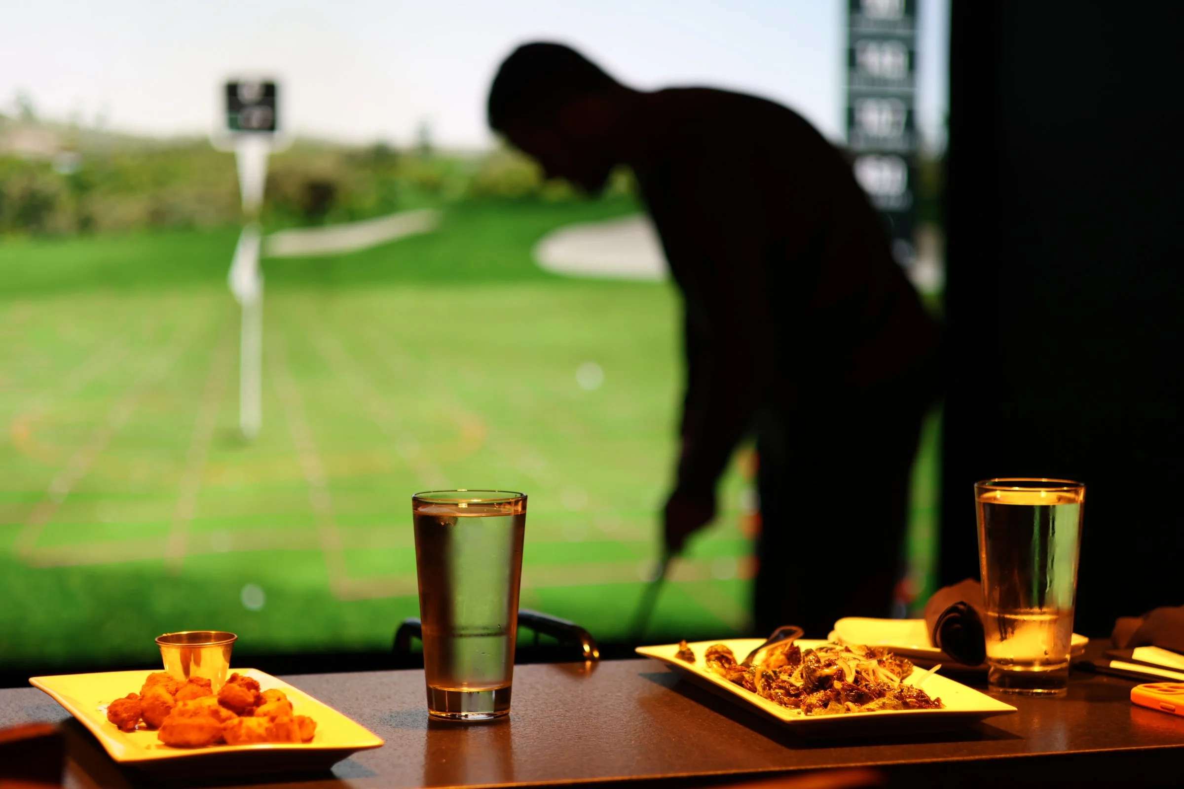 A photo of a patron golfing, snacks, and drinks at The Club in Lemont, Illinois.