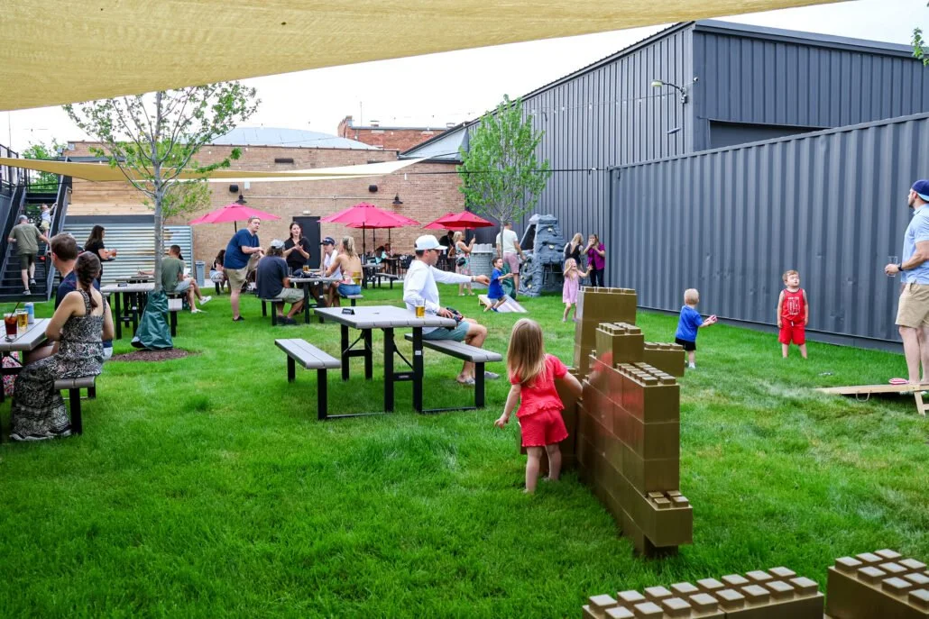 A photo of families playing outdoors and enjoying their meals at back yard patio at The Club in Lemont Downtown.
