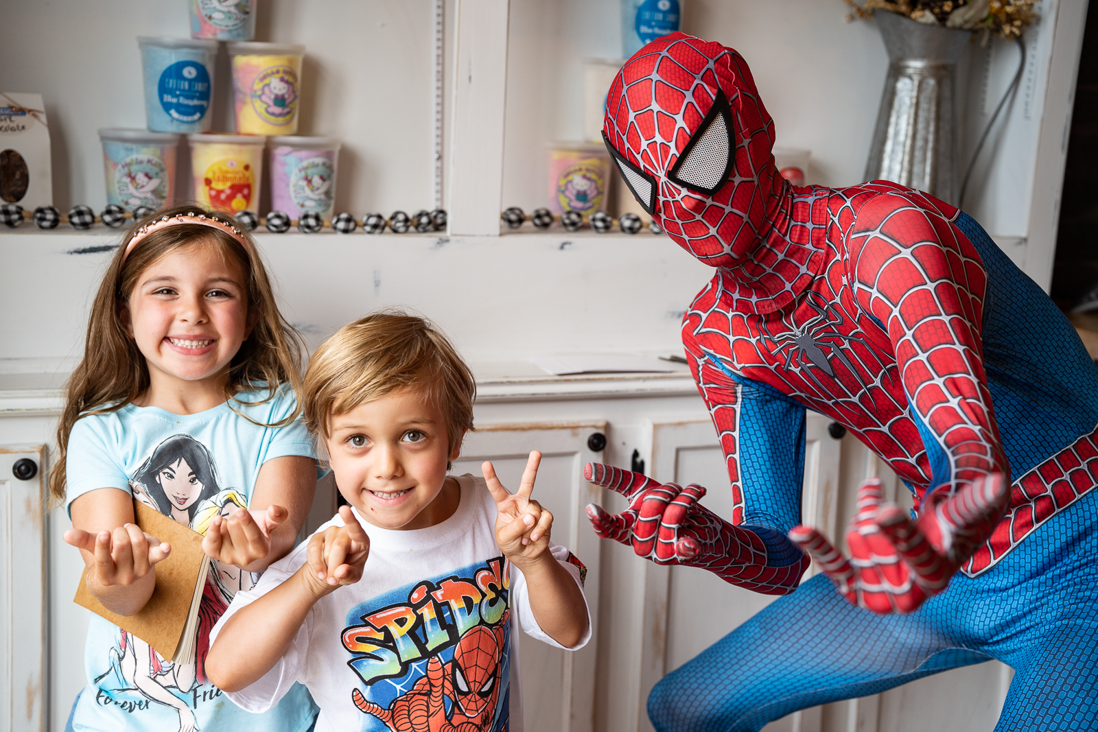 Spiderman posing with two kids making the spiderman pose.