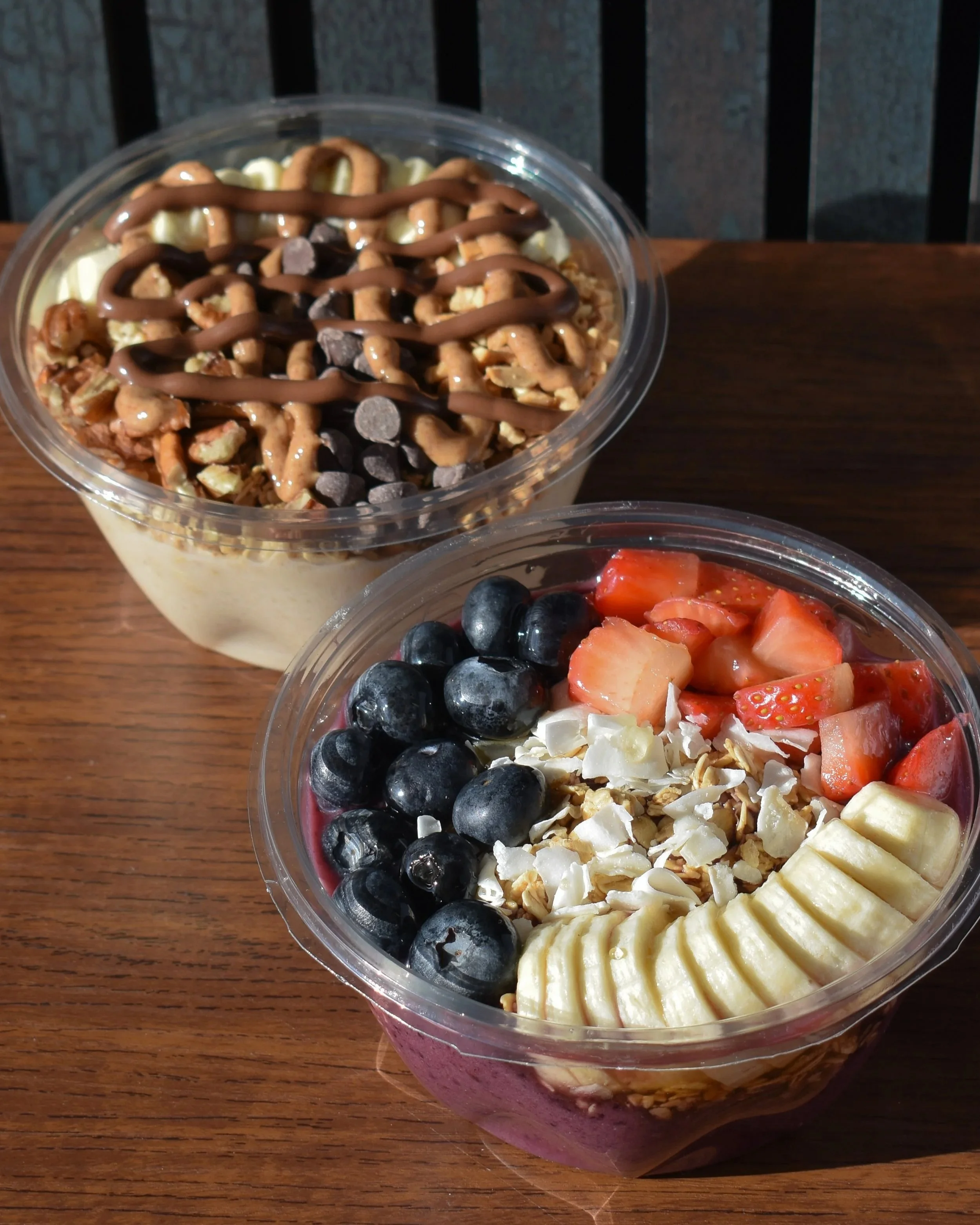 Two loaded smoothie bowls from The Daily Blend, an acai bowl and a banana chocolate bowl