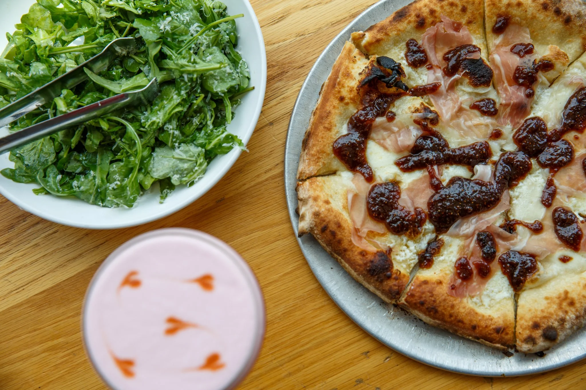 A photo of wood-fired pizza, a cocktail, and a salad at Wooden Paddle Lemont, in Lemont Downtown, Illinois.