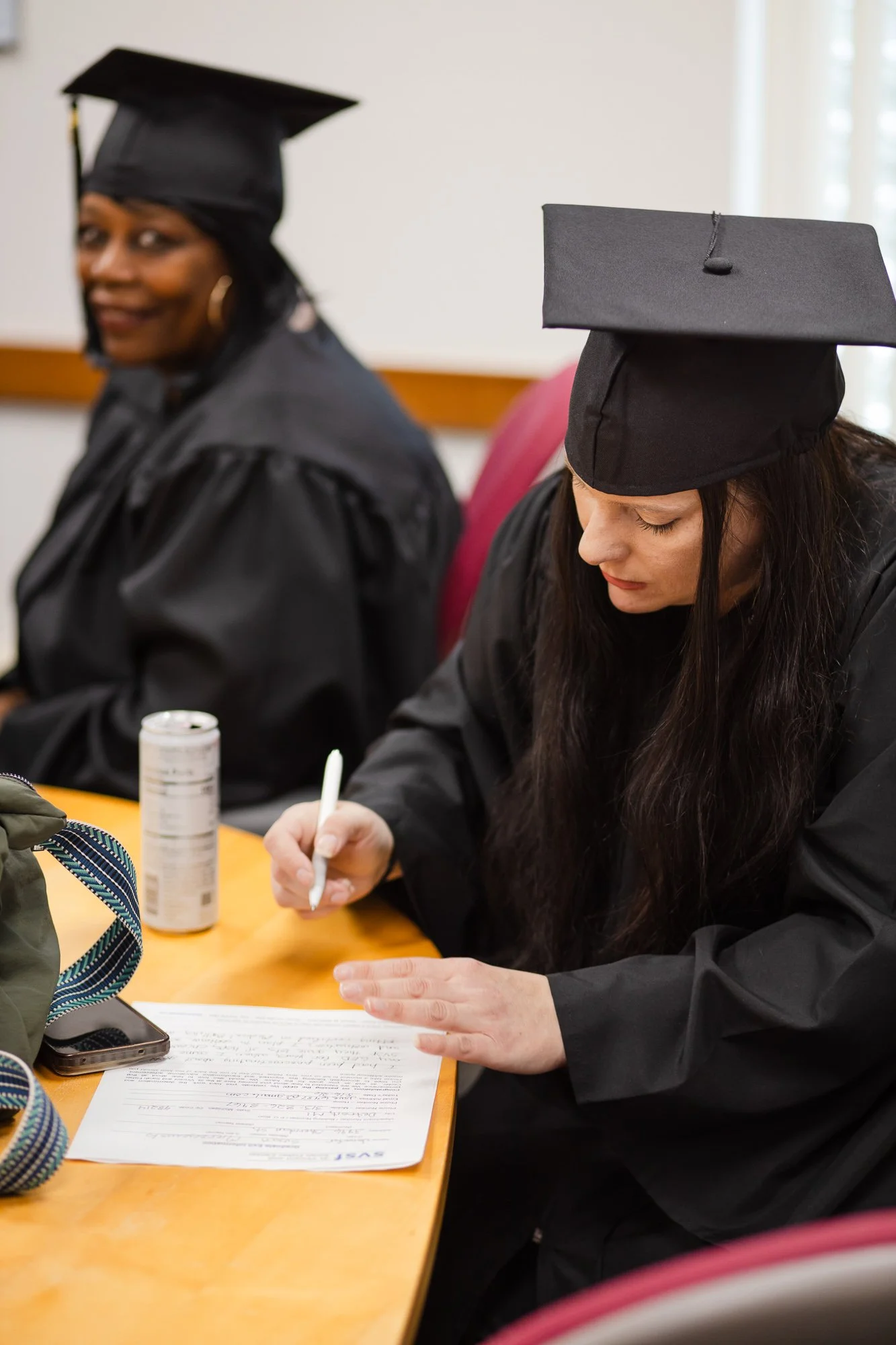 A woman signing her diploma: nonprofit graduation ceremony Detroit event photography.