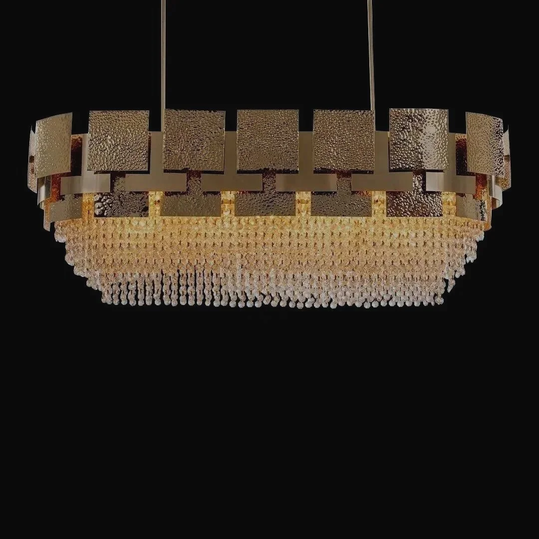 A large, modern chandelier with a circular gold frame, adorned with numerous hanging crystal drops, hanging against a black background.