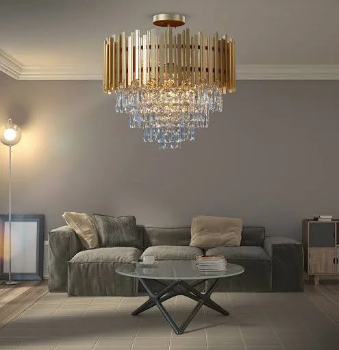 Modern living room with a velvet sofa, a glass coffee table, a gold and crystal chandelier, and a standing floor lamp.
