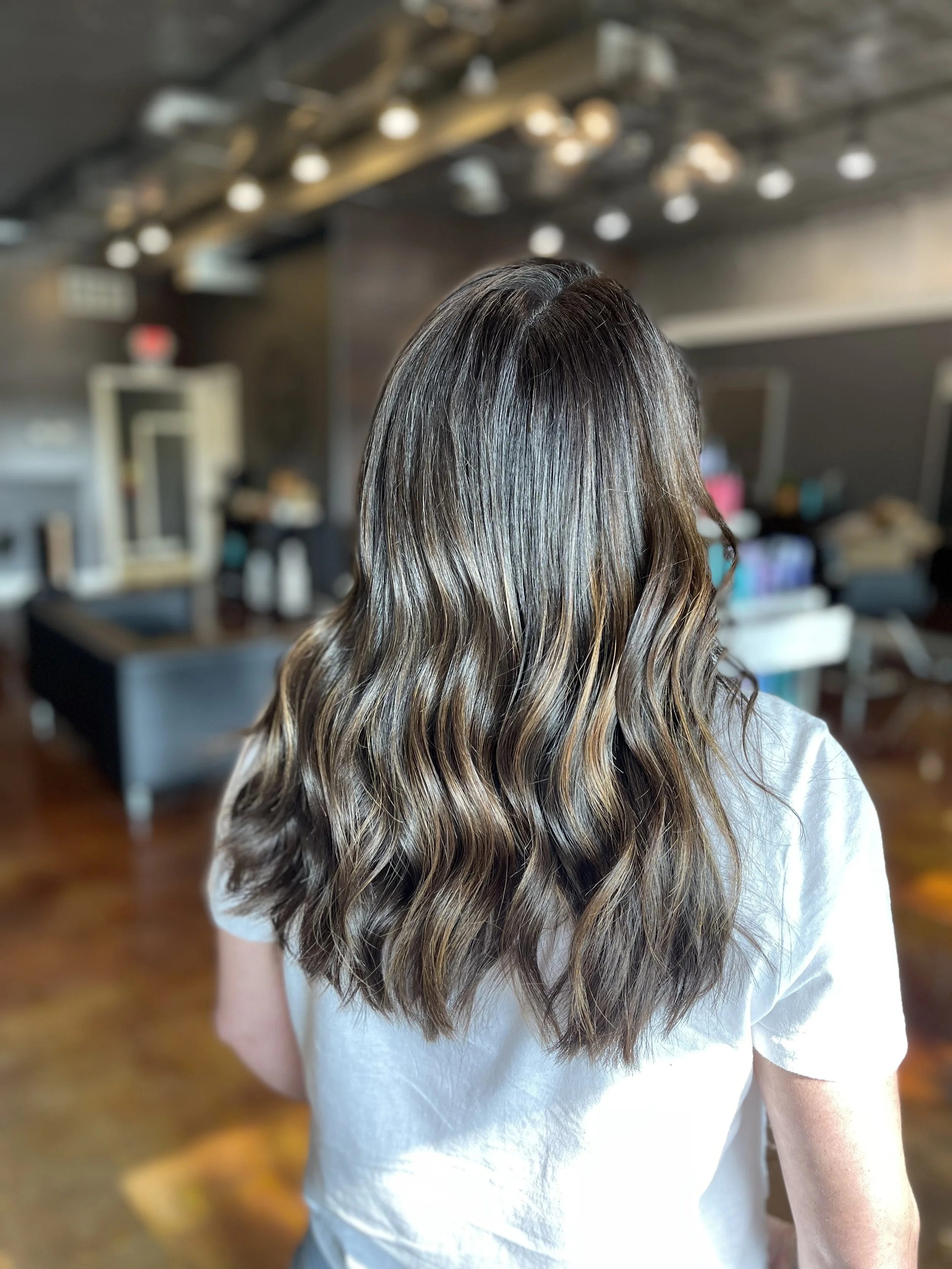 Brunette balayage with soft waves on shoulder-length hair, styled at The Nicole Martin Salon in St. Louis.
