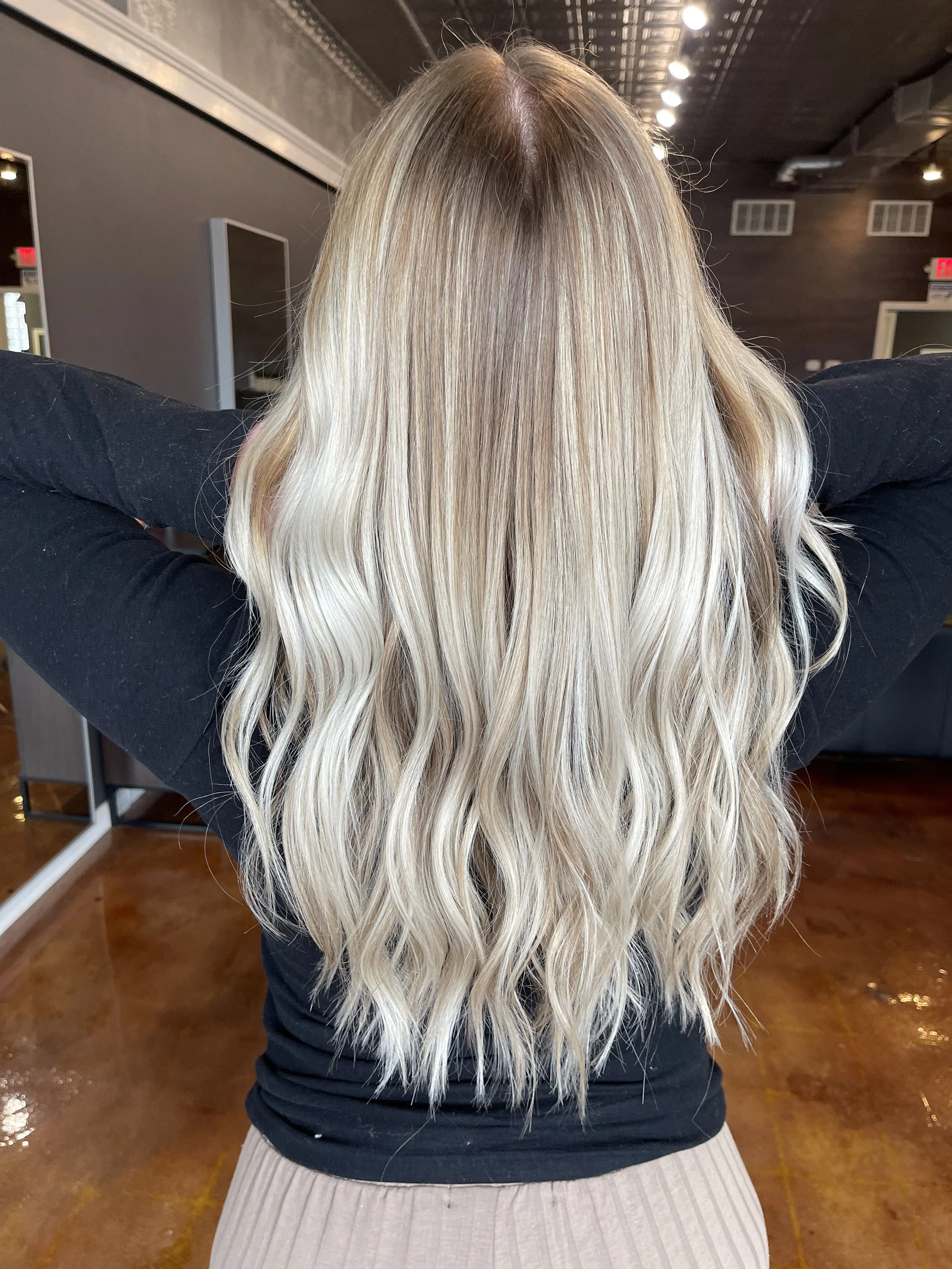 Blonde balayage with soft waves on long hair, styled at The Nicole Martin Salon in St. Louis.