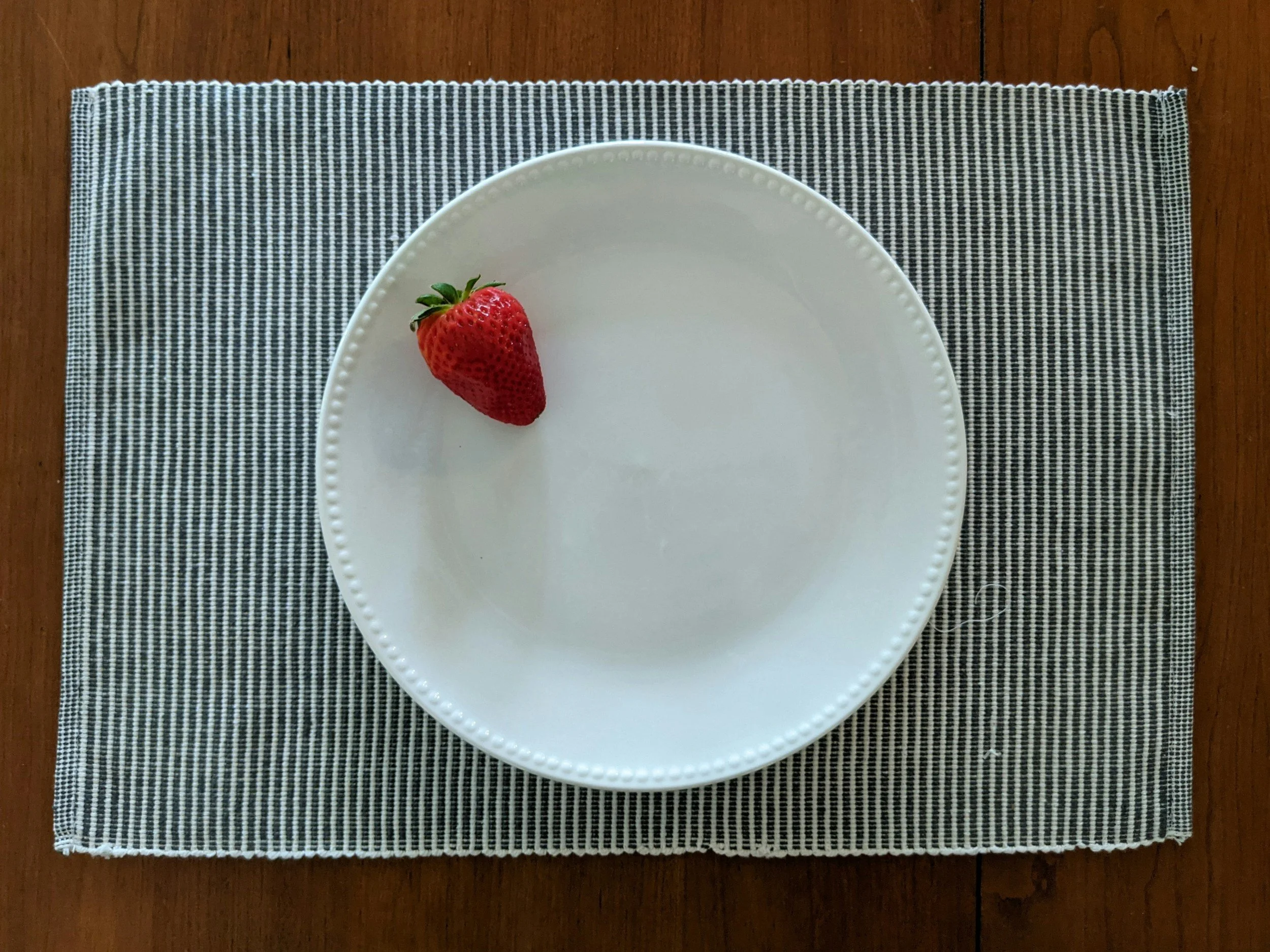 Image shows a single strawberry on a plate. This demonstrates the restriction often created by ARFID, an earing disorder.
