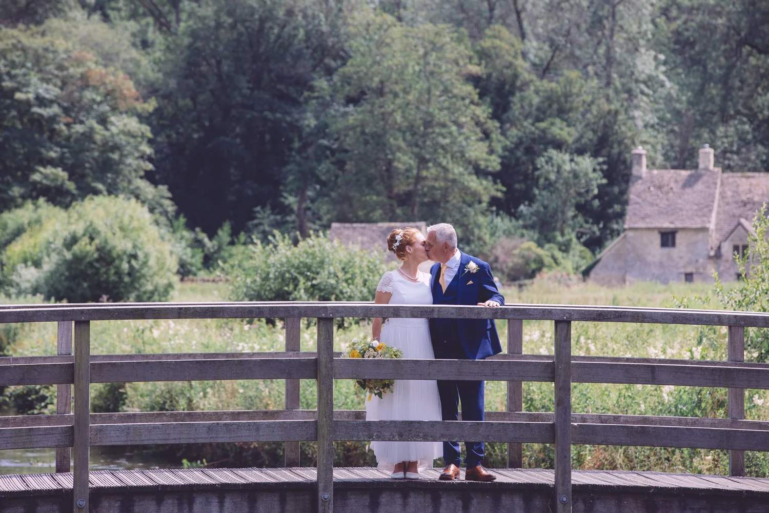 Couple kissing on the footbridge by The Swan, Bibury
