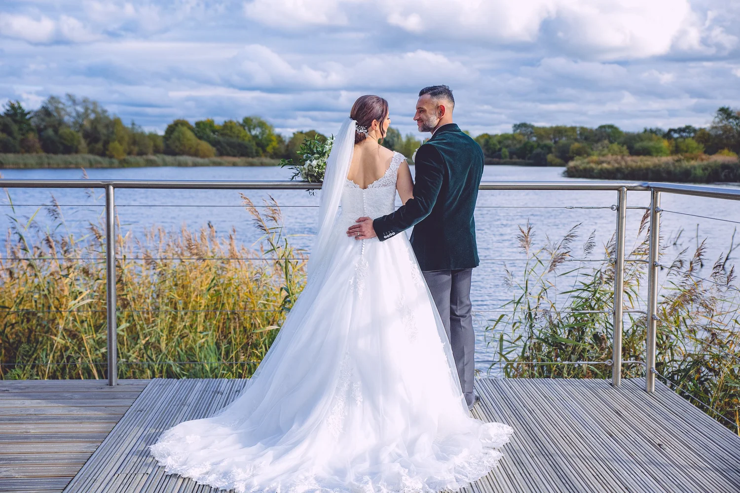 Bride and groom on a lakeside jetty at De Vere Cotswold Water Park