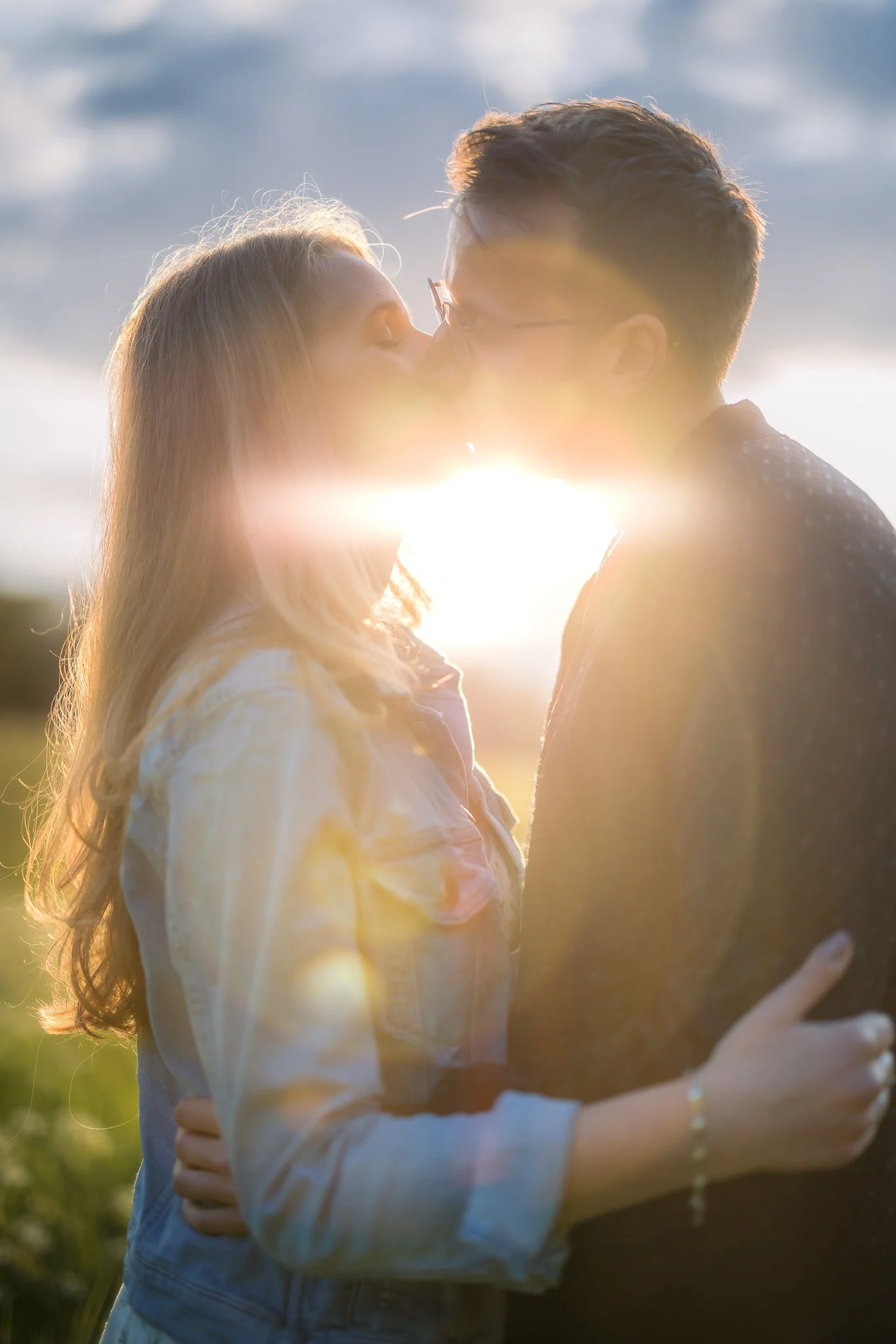 Engaged couple kissing in golden sunlight