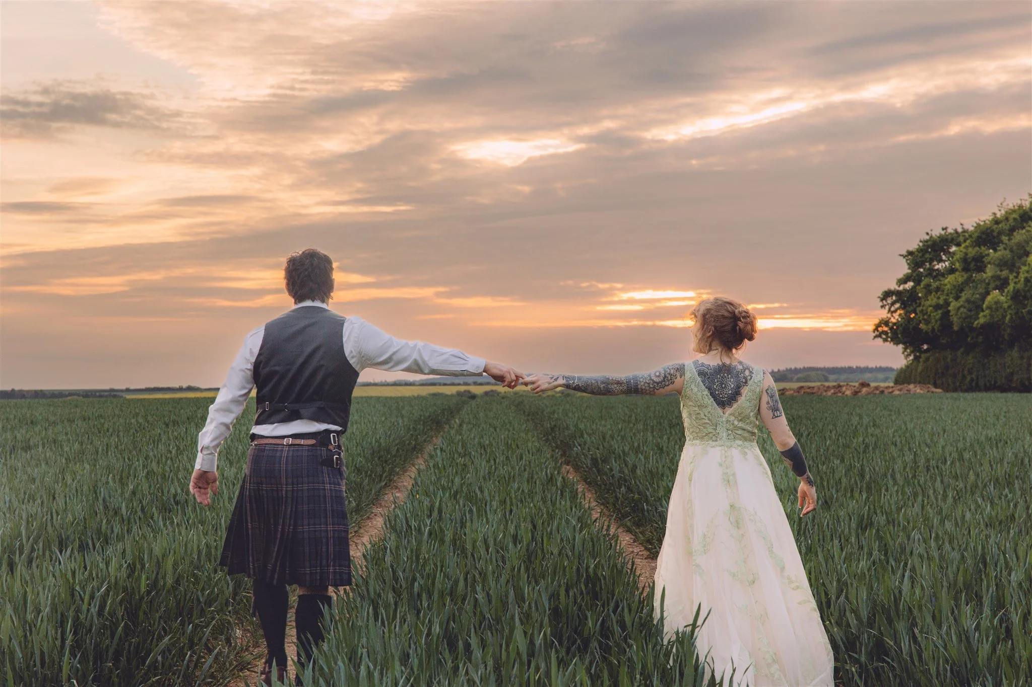 Couple holding hands in a field at sunset