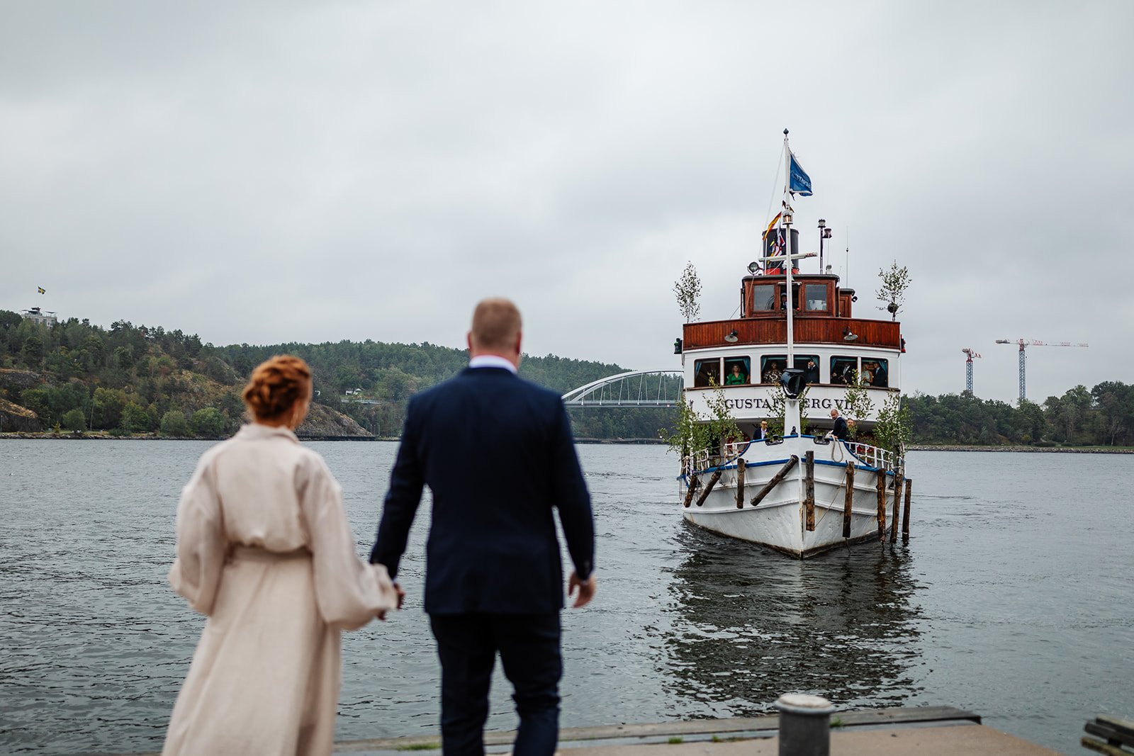 bröllopspar som håller varandras händer och väntar på färjan som ska ta dem till Stockholms skärgård