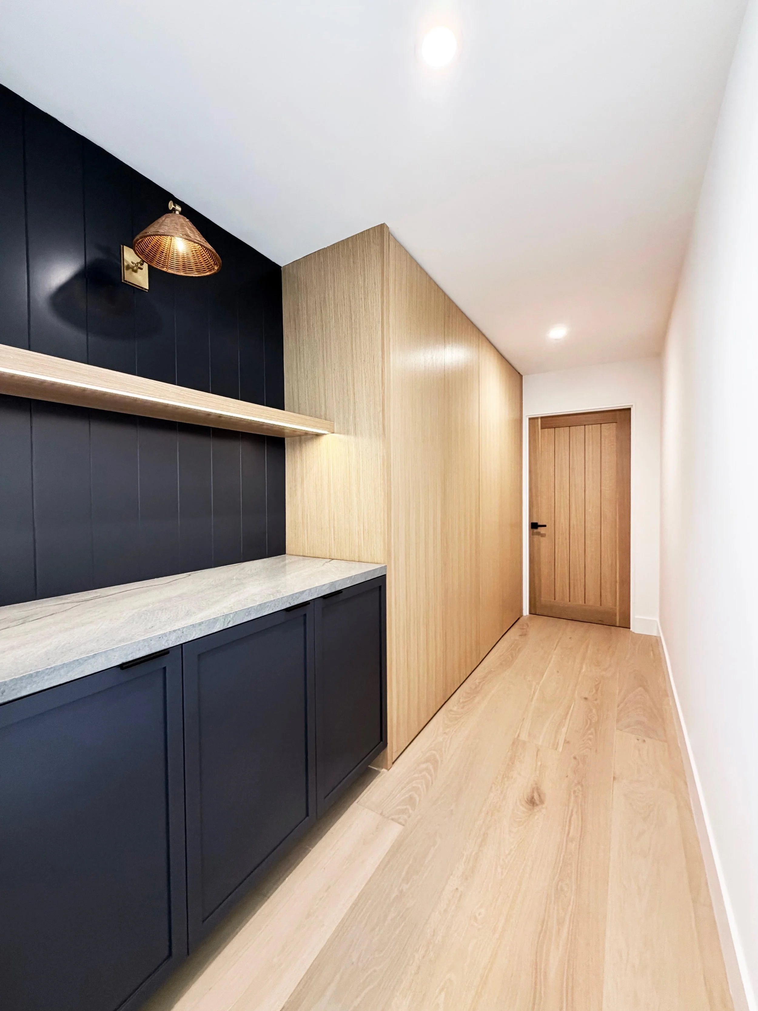 Coastal laundry room with blue accent wall and white oak cabinetry