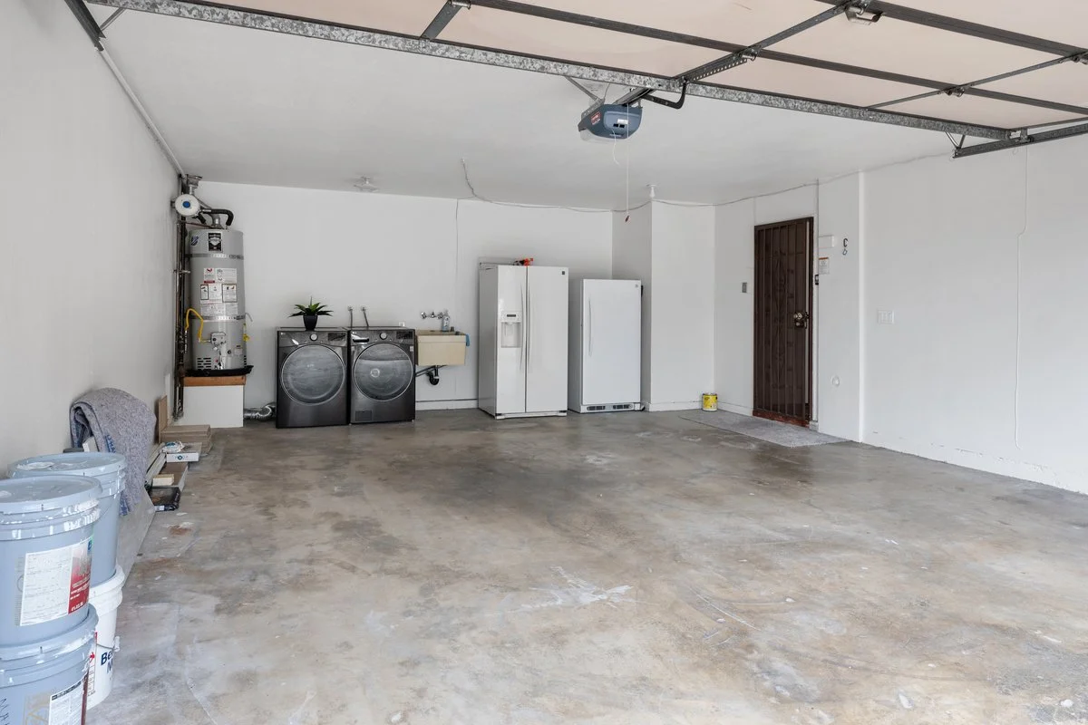 Empty garage with laundry appliances, a refrigerator, and storage containers