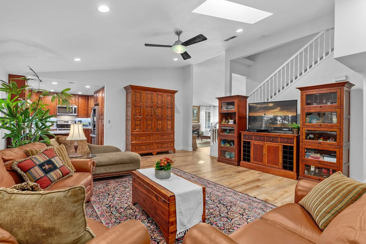 Living room with leather sofas, wooden furniture, a large TV, and a staircase.