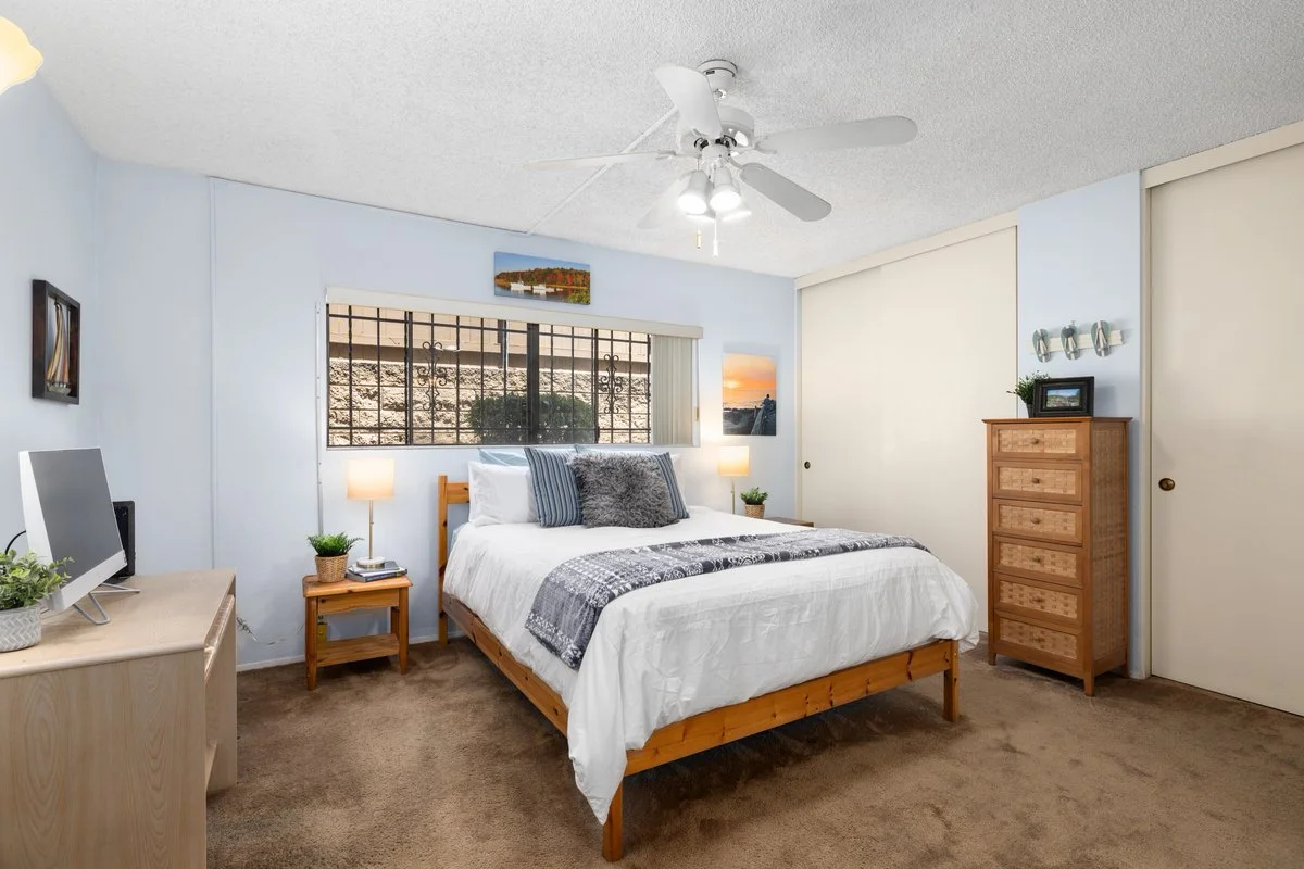 A bedroom with a bed, nightstands, a dresser, a ceiling fan, and wall decorations.