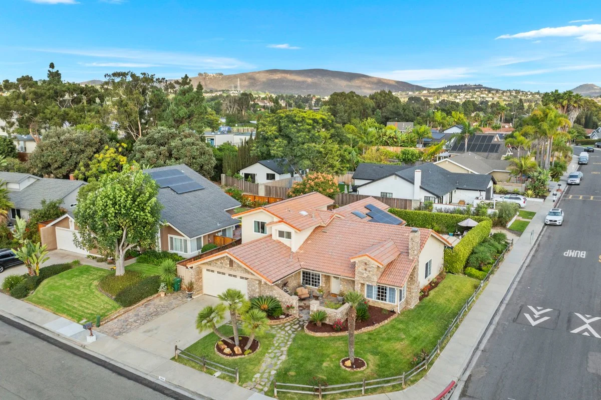  aerial view of a suburban neighborhood with houses, trees, and a mountain in the background